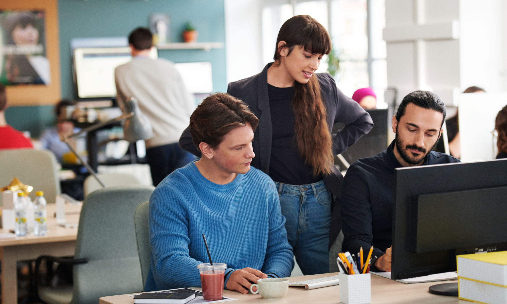 Three colleagues by a computer screen.