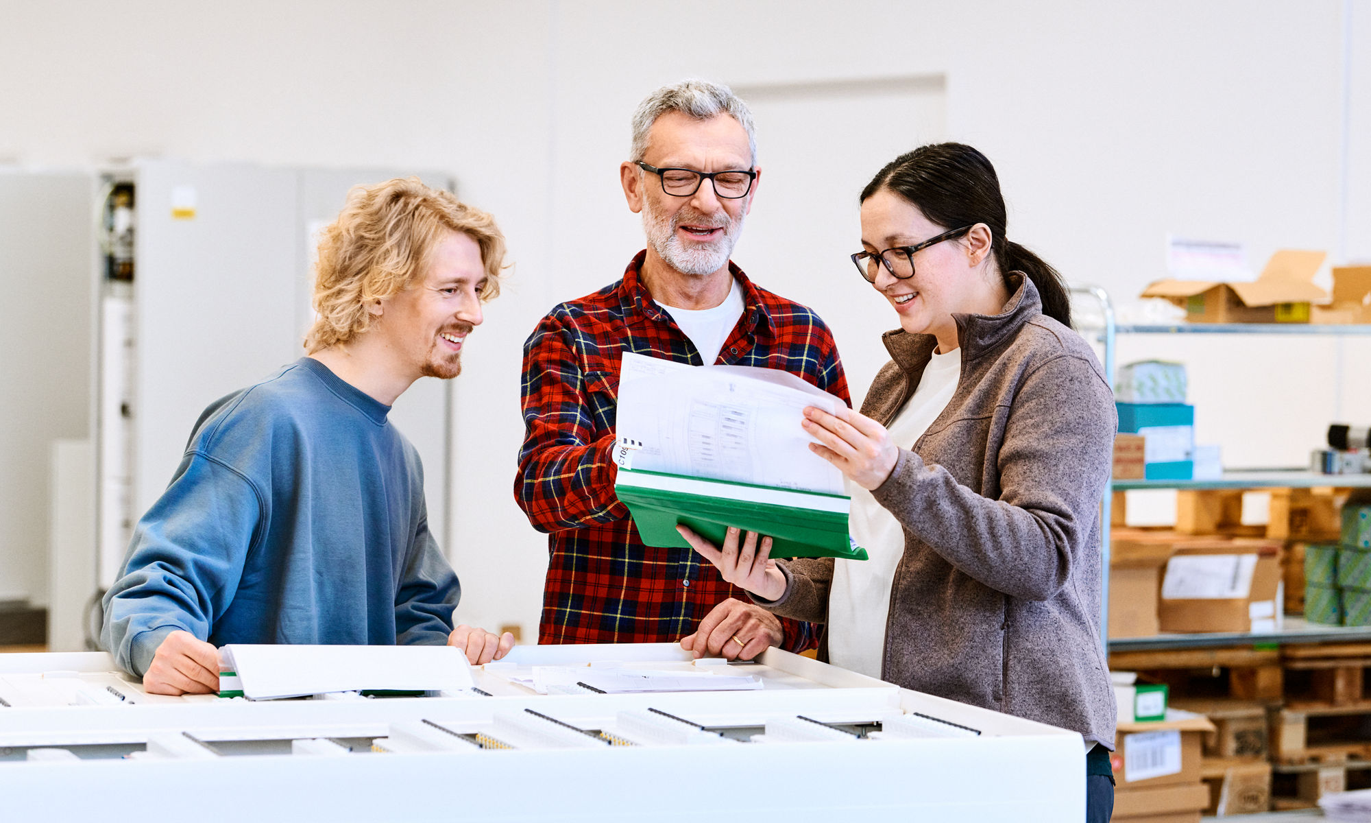 Två män och en kvinna på kontoret som tittar i en plastmapp.