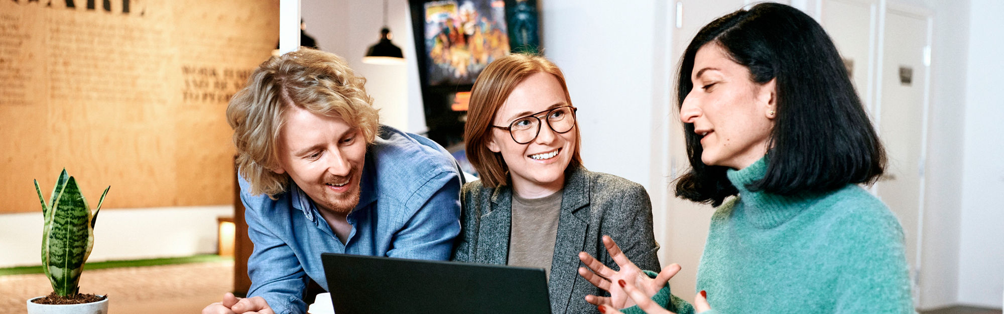 Two women and a man at a desk with a laptop.