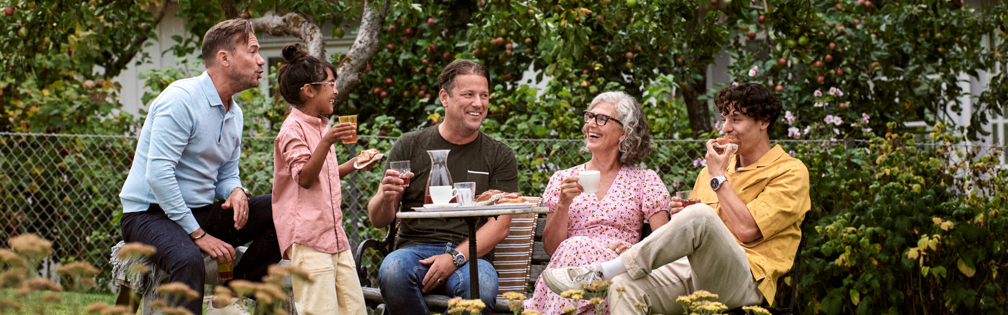 Children and adults in the garden having a fika.