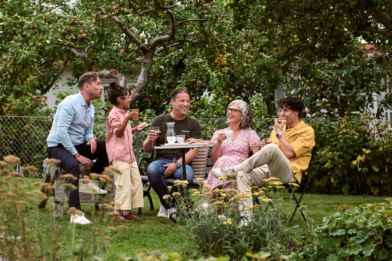 Children and adults in the garden having a fika.