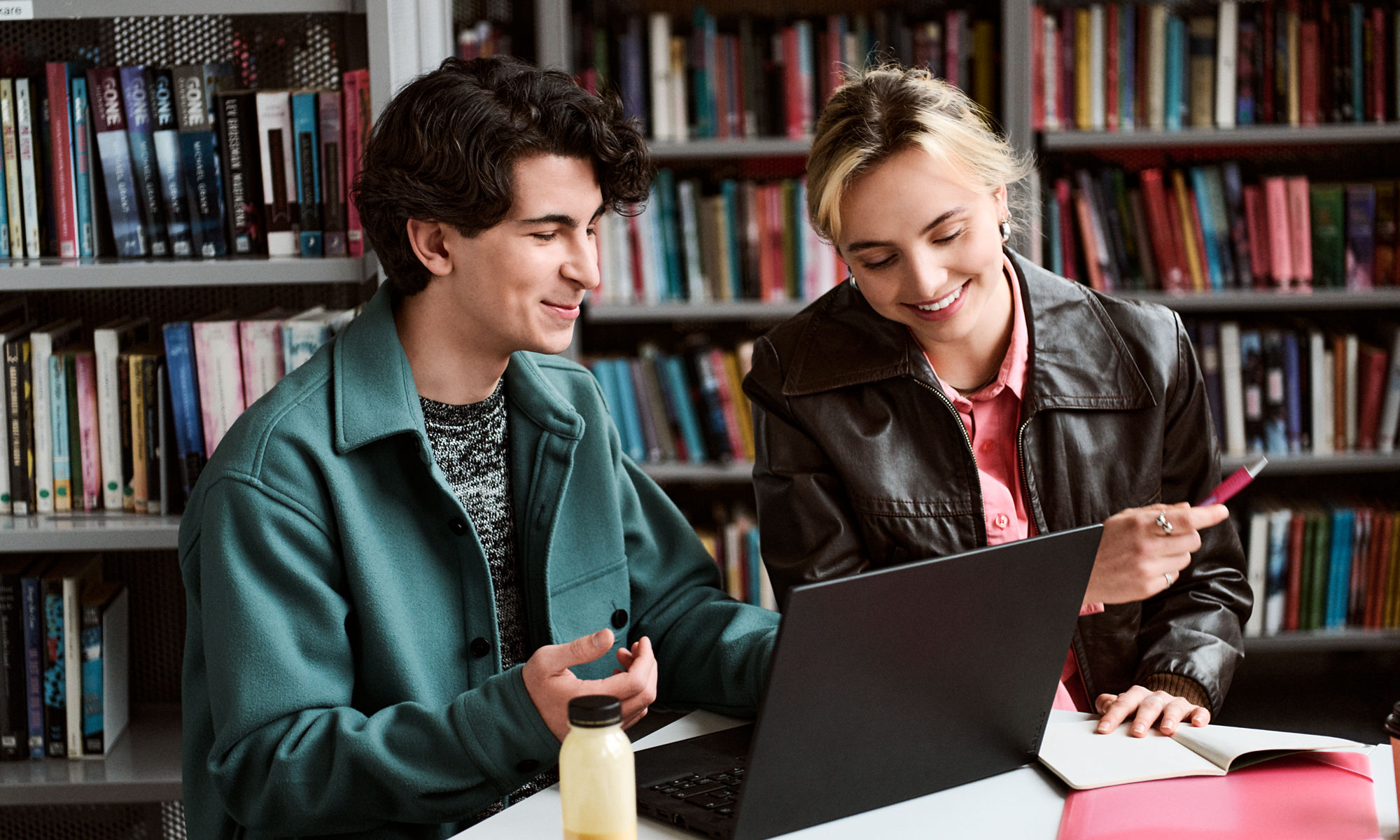 Två studenter sitter och pluggar tillsammans i ett bibliotek