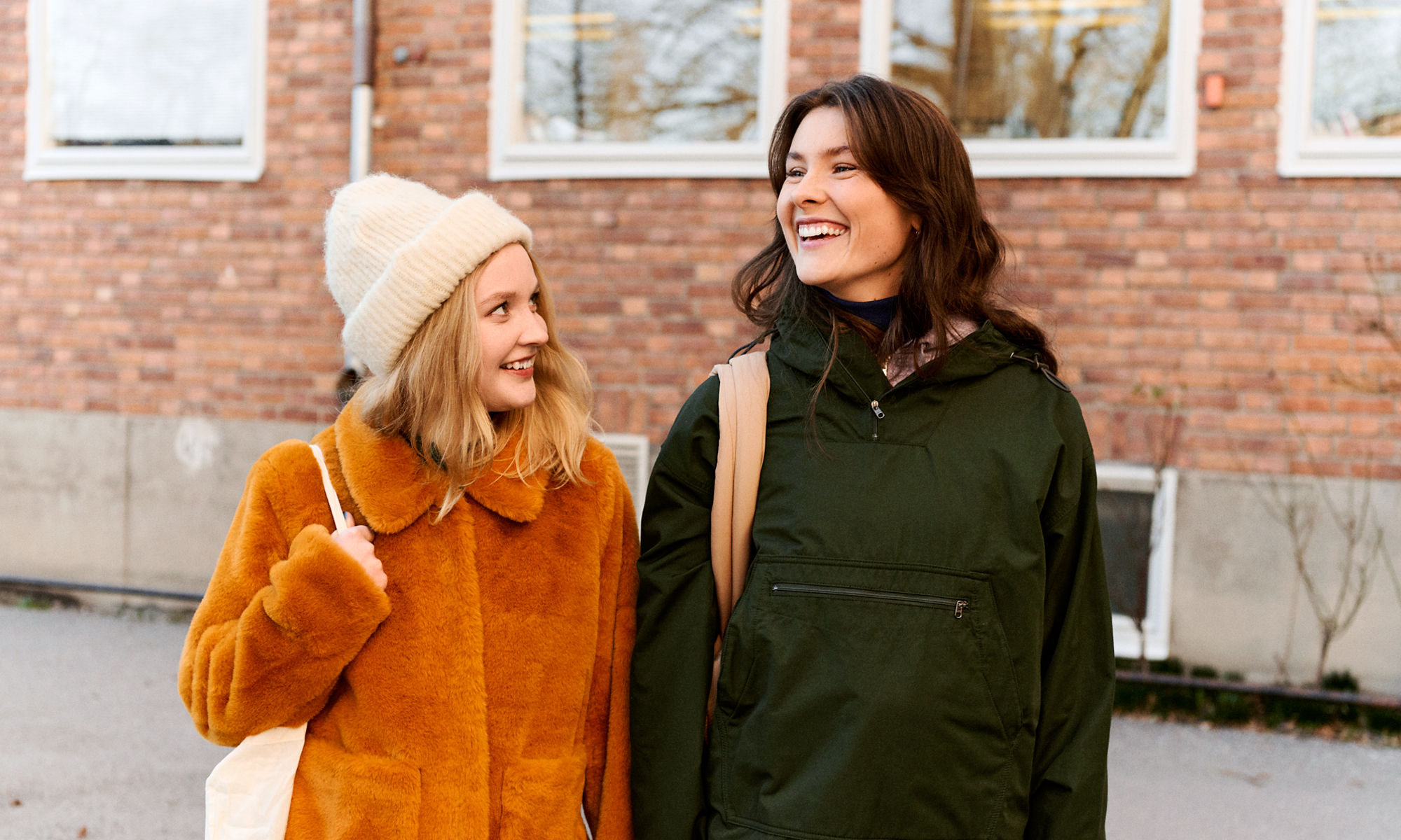 Två kvinnliga studenter är ute och går på en skolgård