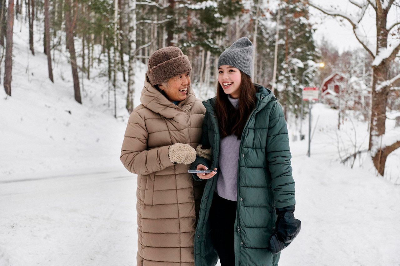 En äldre kvinna och en ung tjej promenerar tillsammans i snön