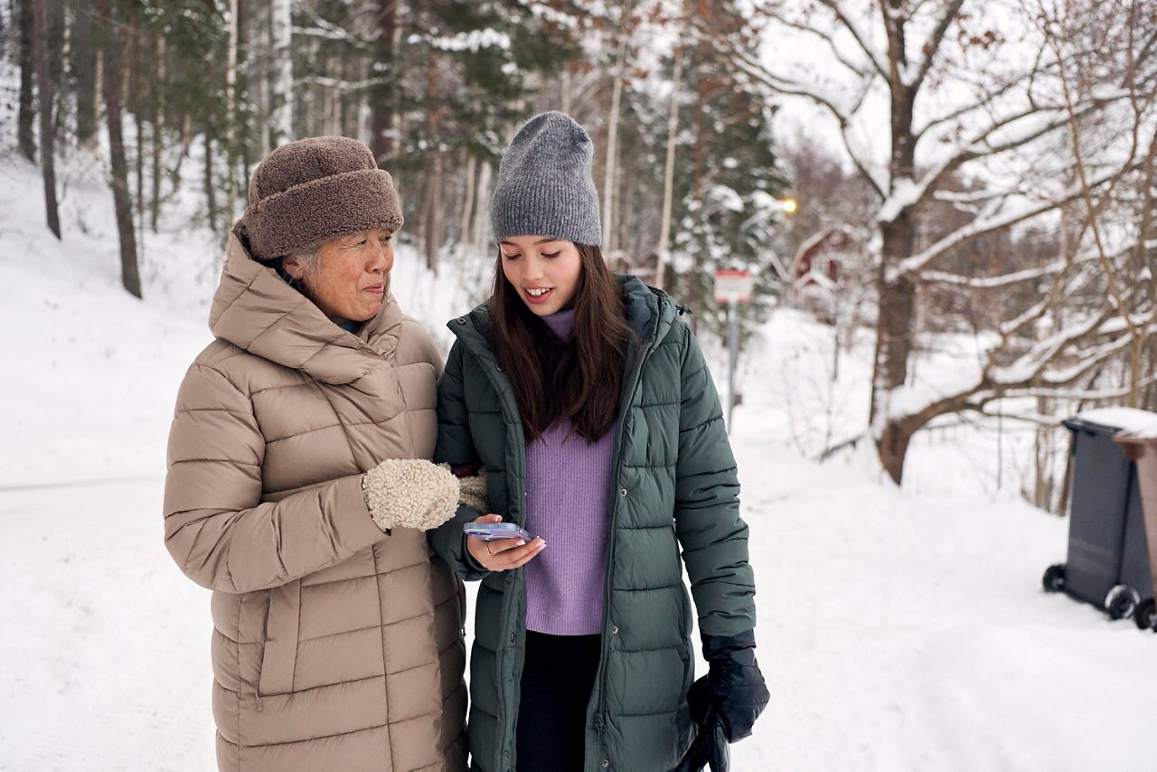 En äldre kvinna och en ung tjej kollar i en mobil tillsammans