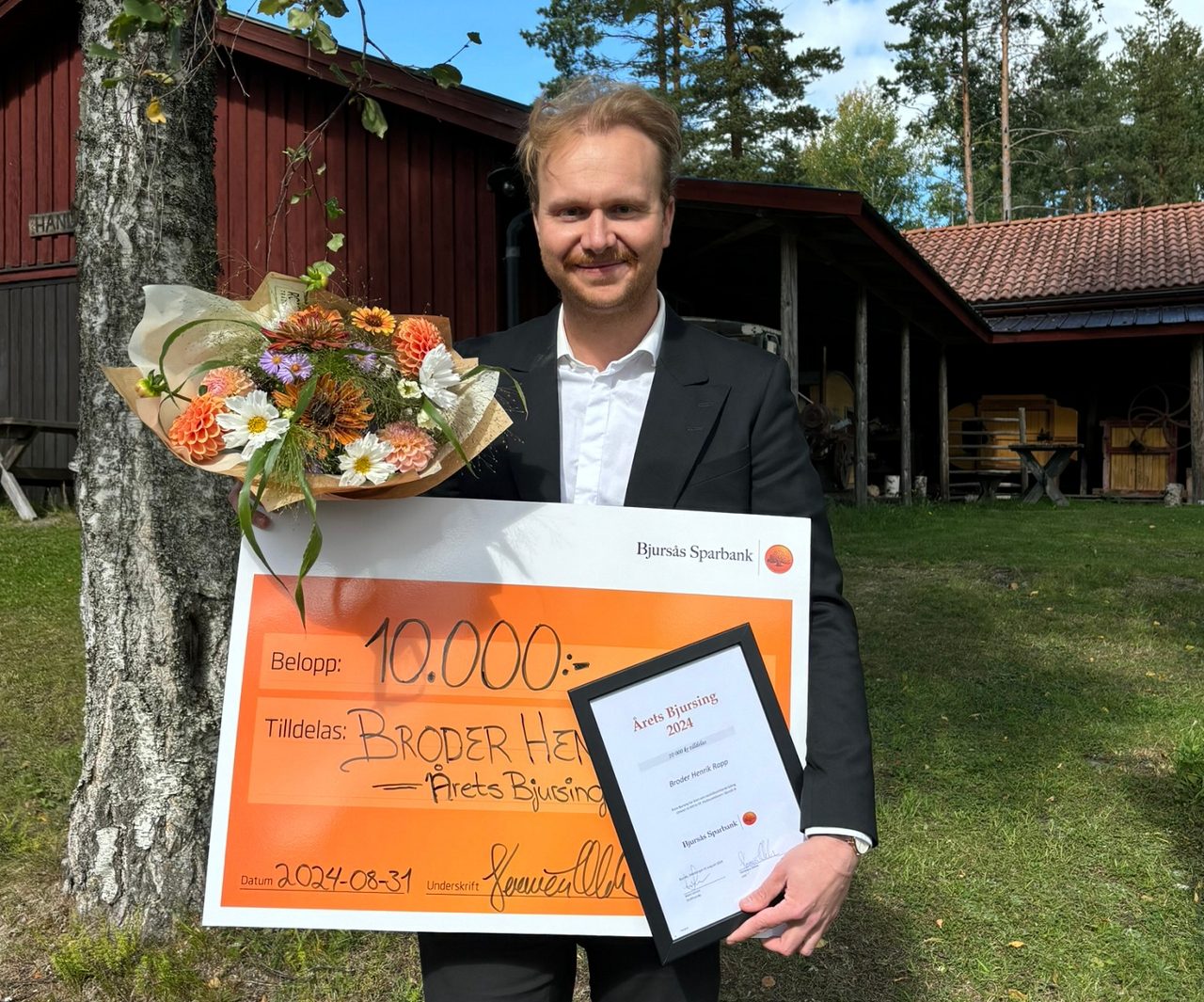 Person som håller ett diplom, en stor vinstcheck och en blombukett