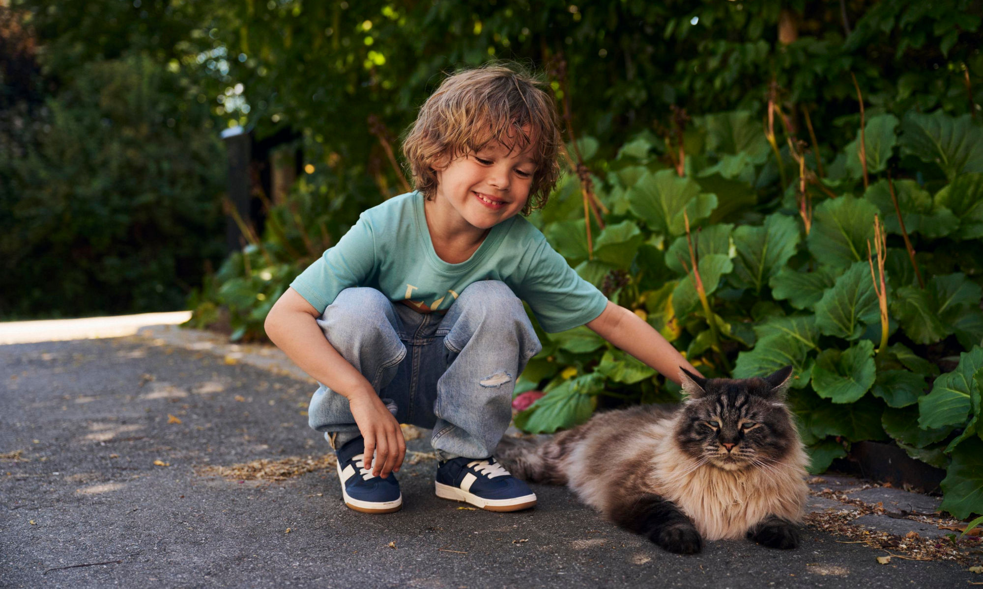 En liten pojke klappar en katt