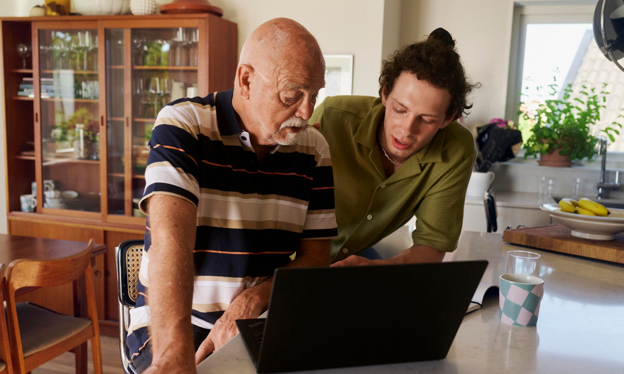 En ung man och en äldre man pratar framför en dator
