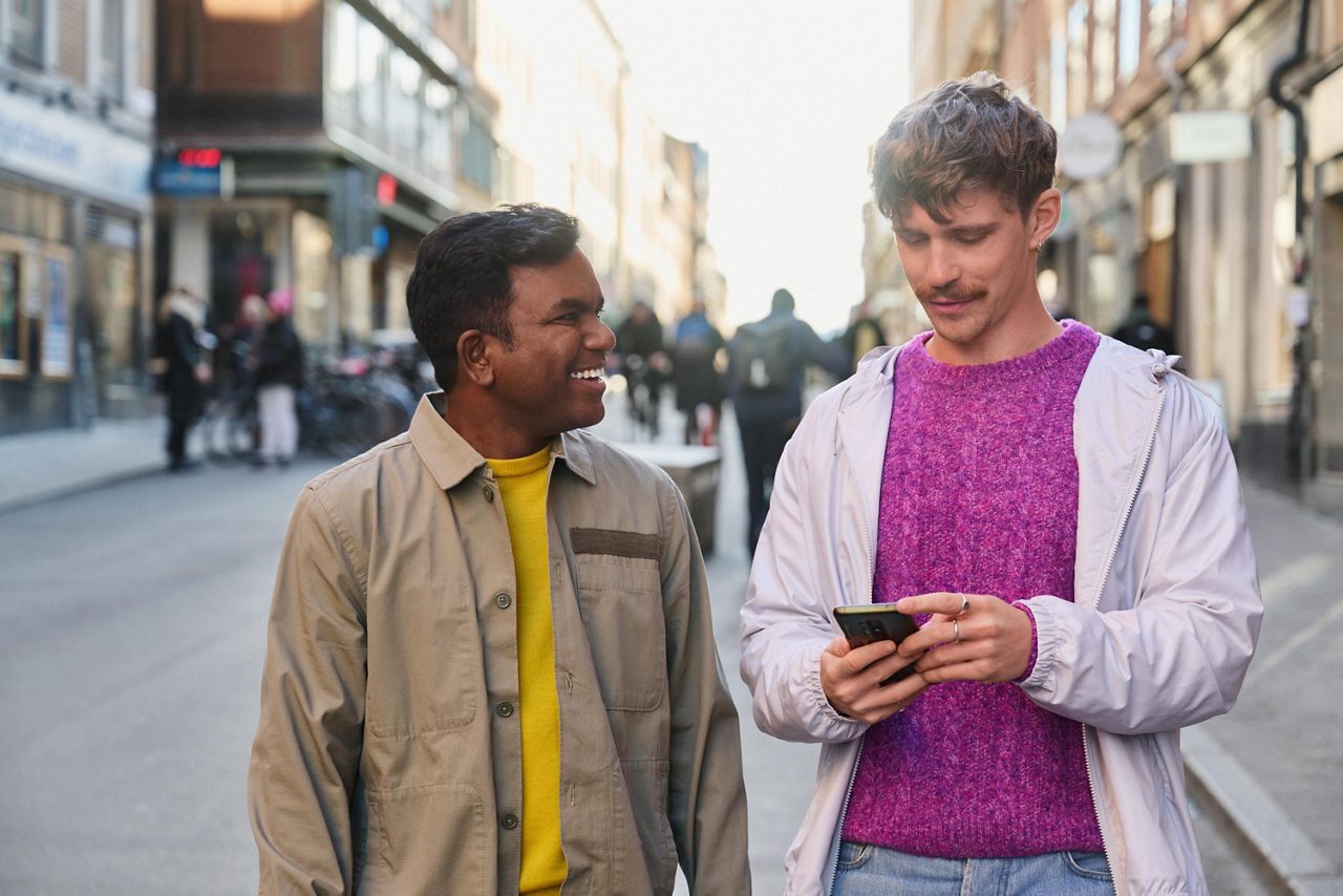Två män som kollar på mobilen tillsammans