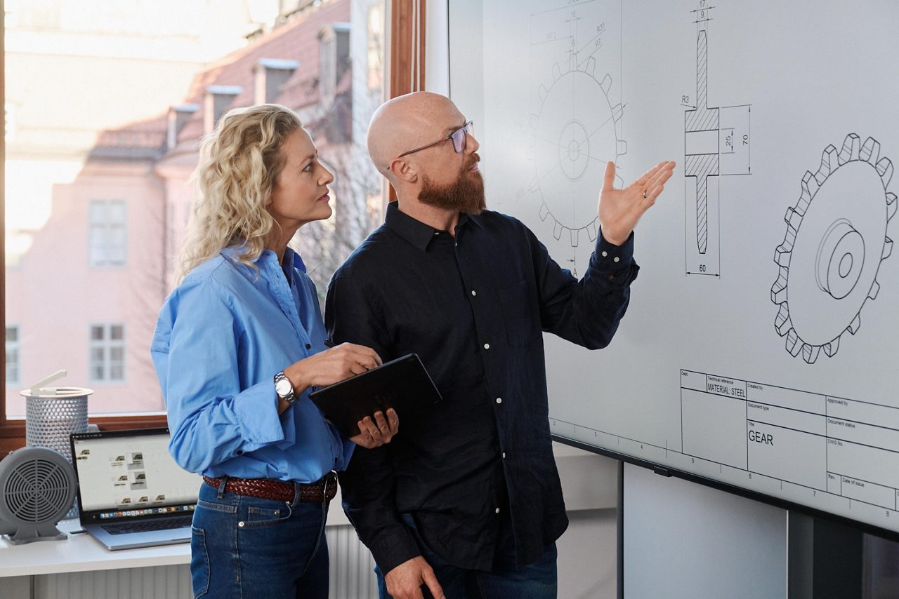 Kollegor som diskuterar en 3D modell framför en stor skärm