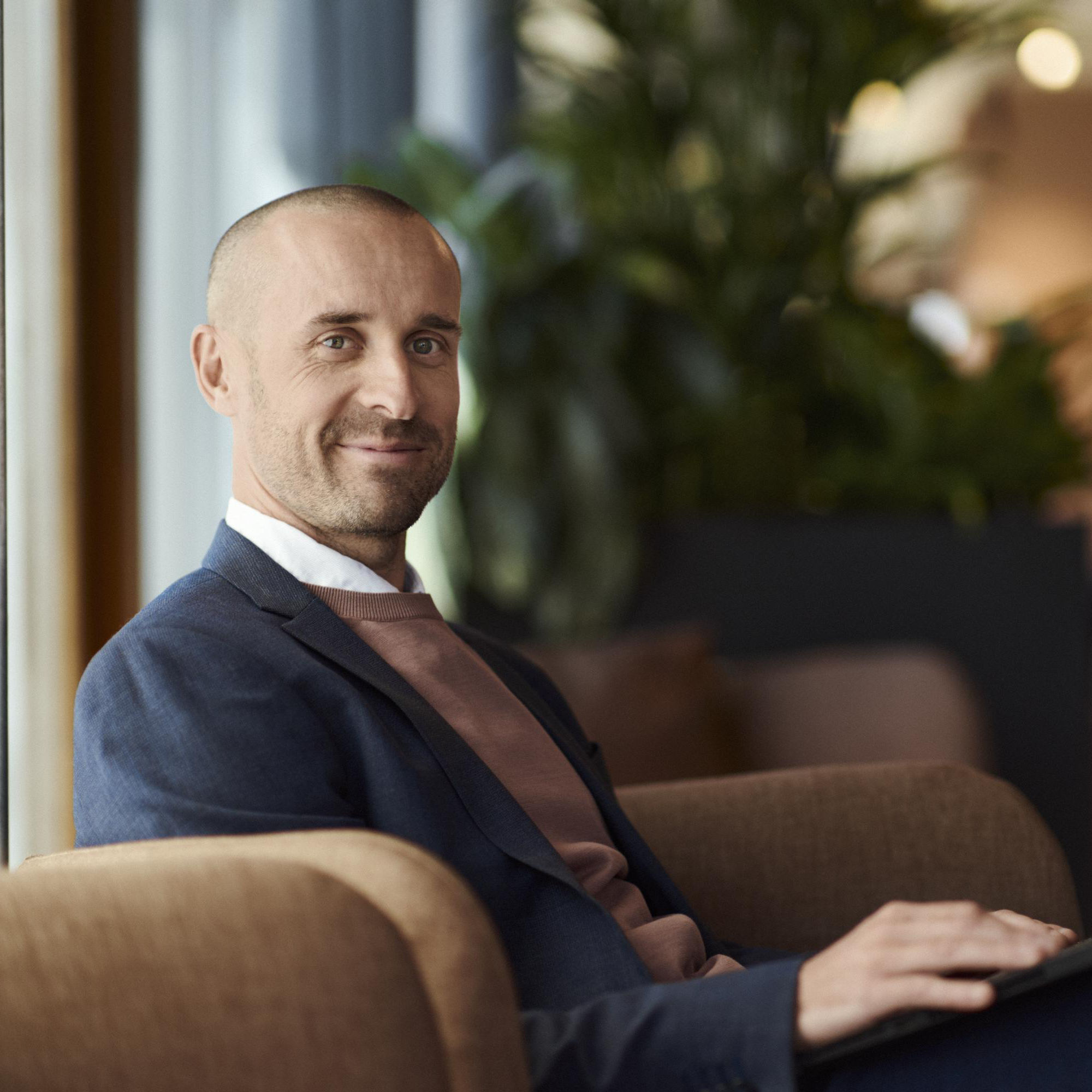 En man sitter i en fotölj med en bärbar dator i knät