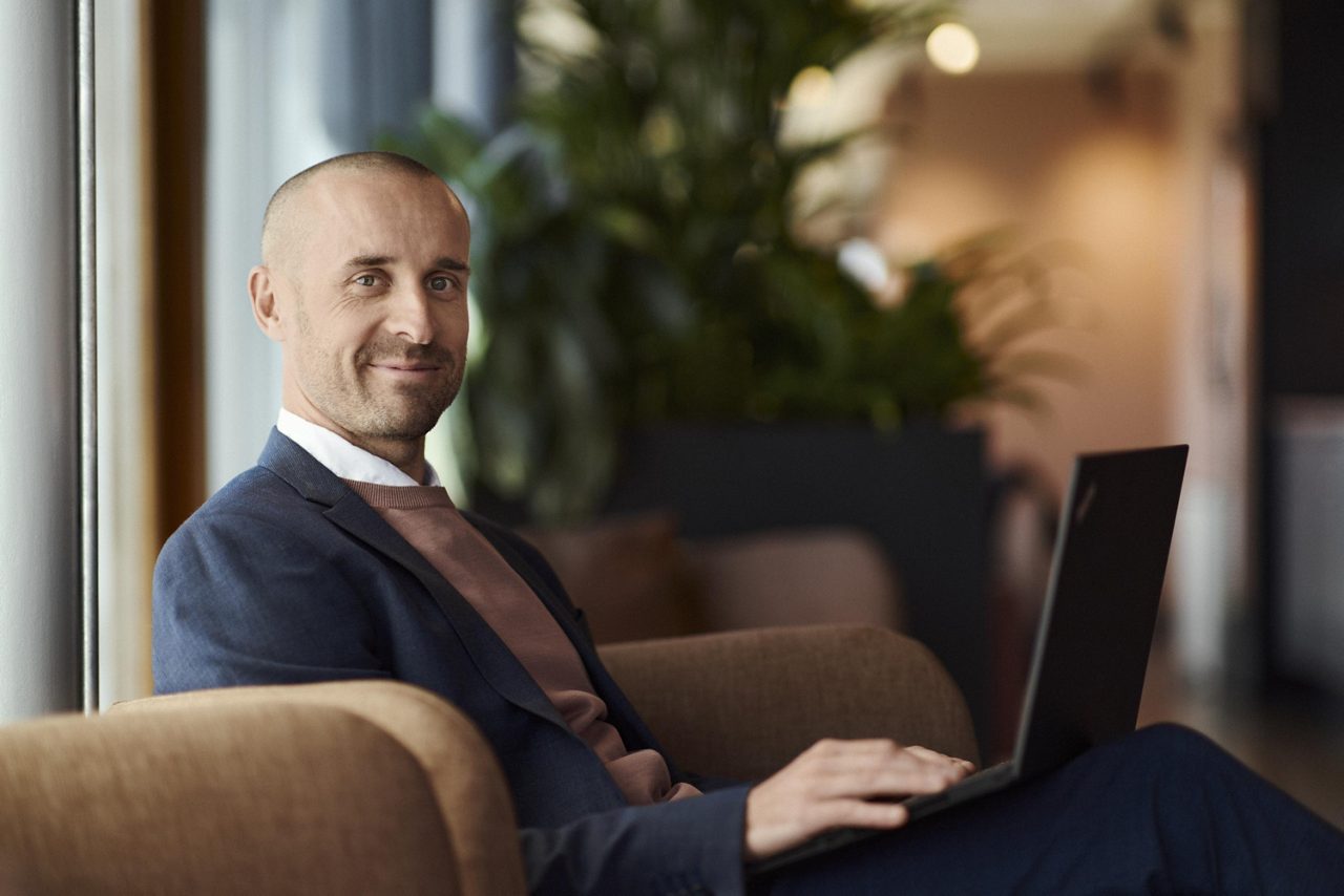 En man sitter i en fotölj med en bärbar dator i knät