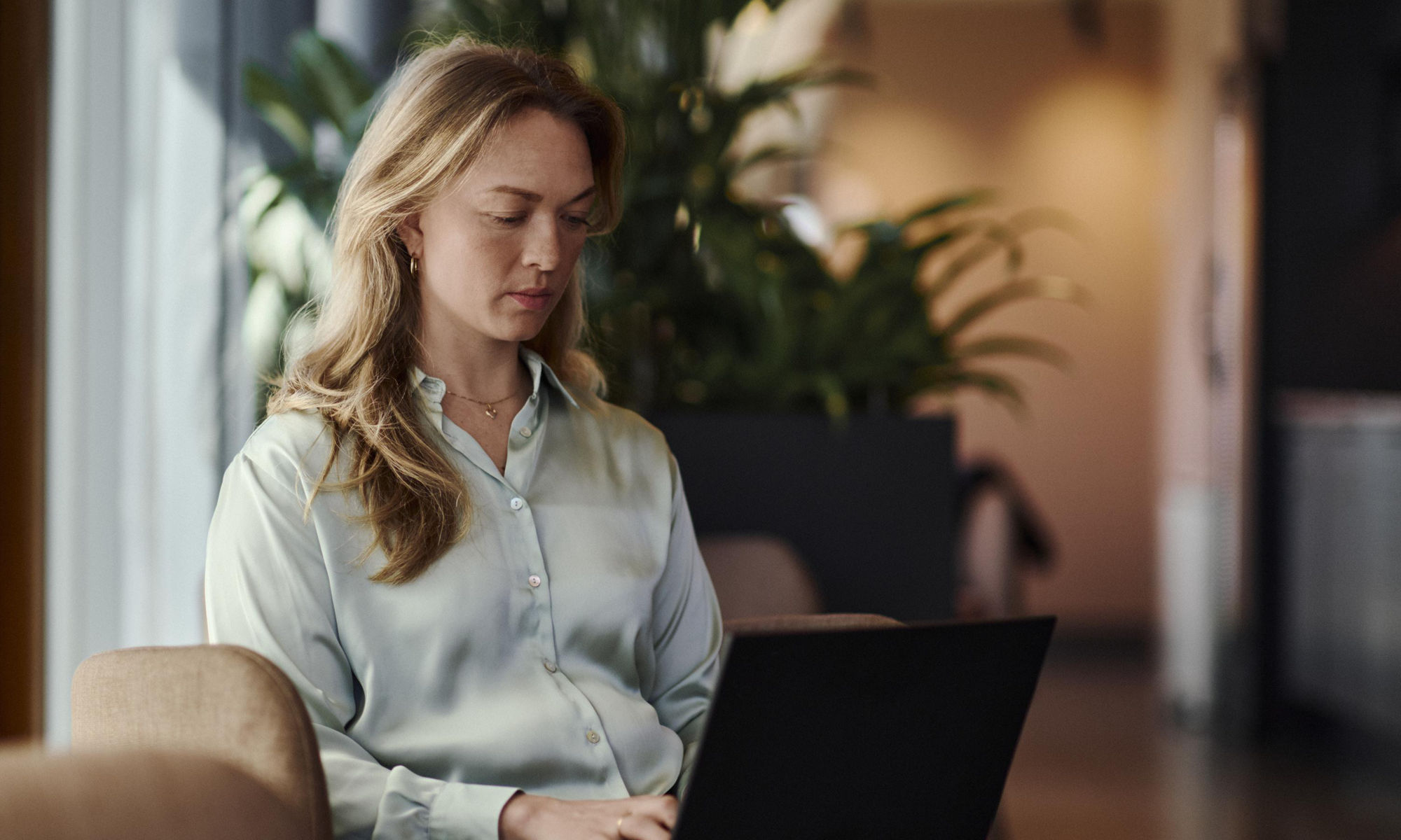 En kvinna sitter i en fotölj och använder en bärbar dator