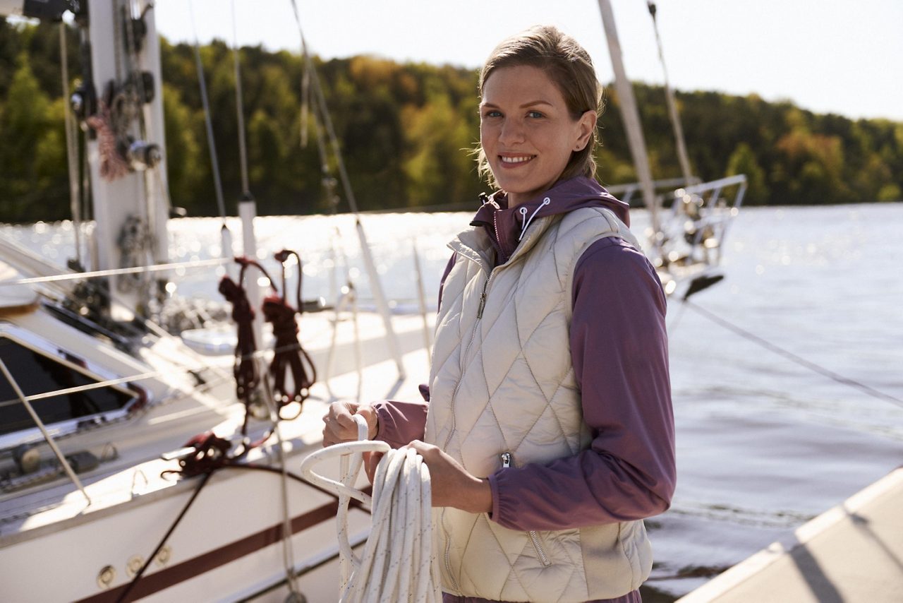 En kvinna står på en segelbåt och håller i ett rep