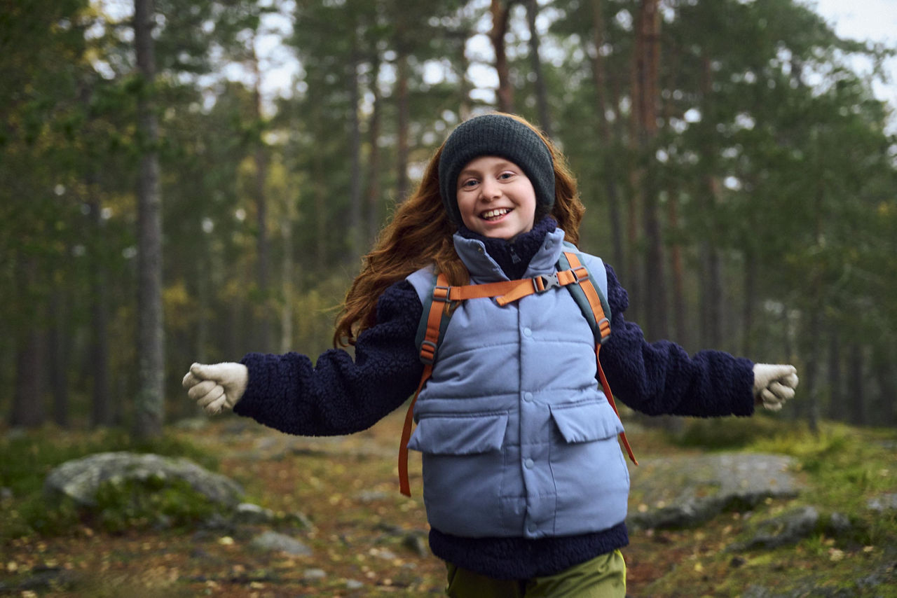 En glad flicka springer i skogen.