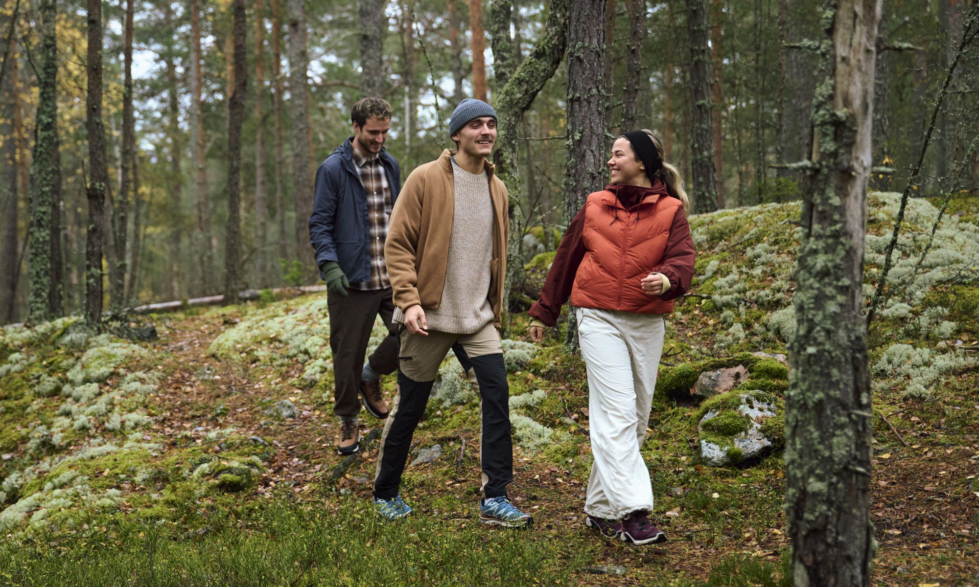 Tre personer promenerar i skogen.