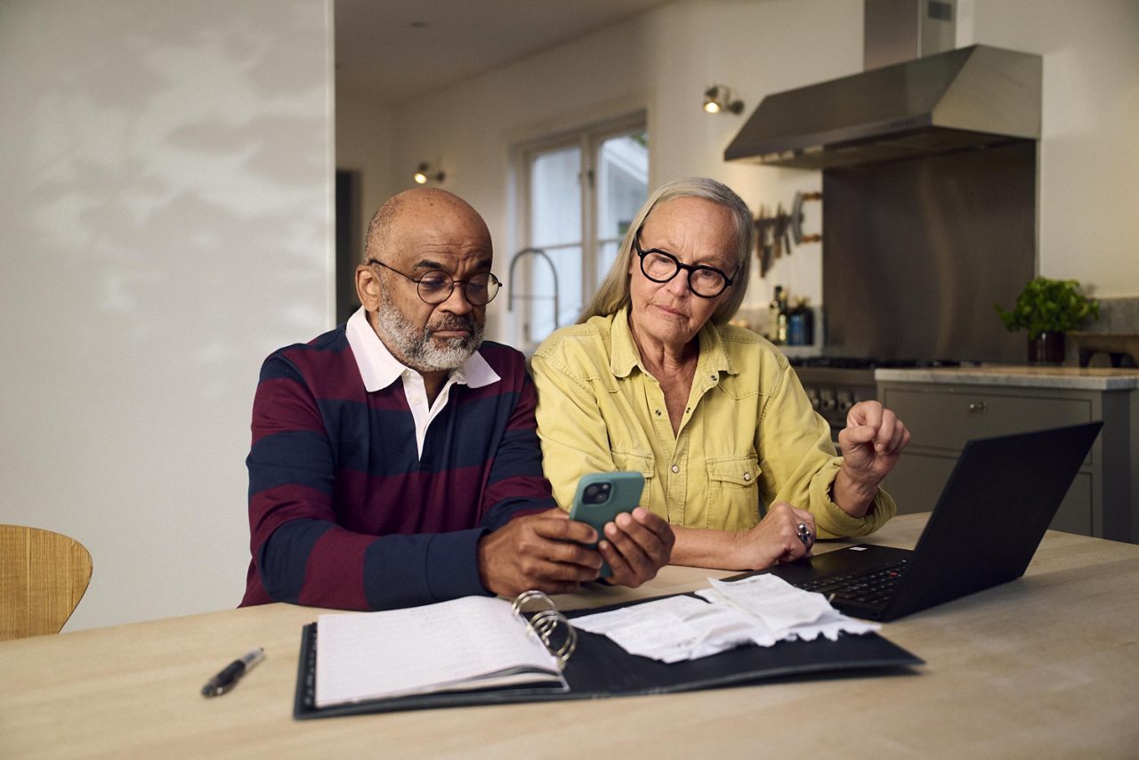 vå äldre personer sitter vid ett köksbord och planerar sin ekonomi.