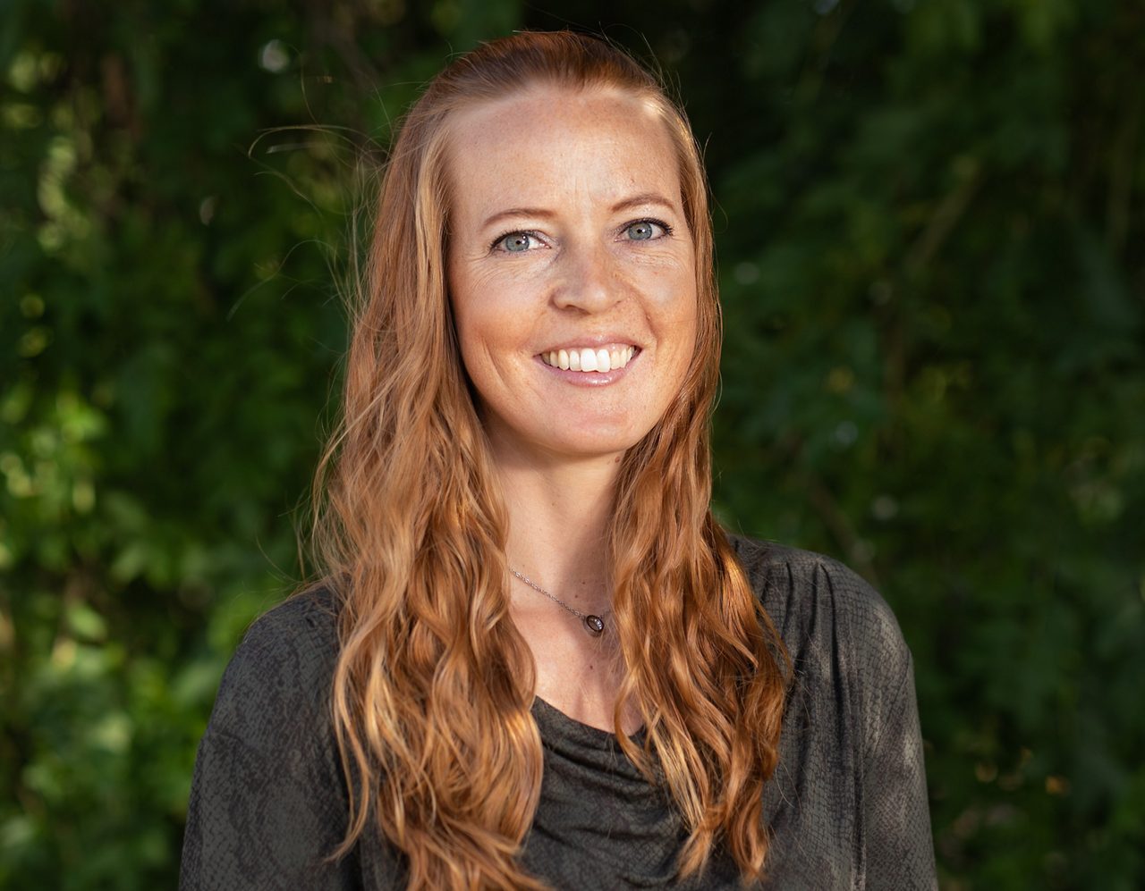 Petra är en av Roslagens Sparbanks premiumrådgivare. Med lång erfarenhet och ett stort engagemang möter hon kunderna med personlig rådgivning och skräddarsydda lösningar. På bilden står hon vid vattnet i en lokal miljö, med den röda träbebyggelsen i bakgrunden.