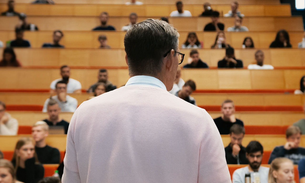 Man föreläser i hörsal på högskola