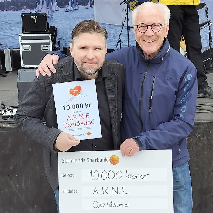 Två män som håller i en check och i ett diplom