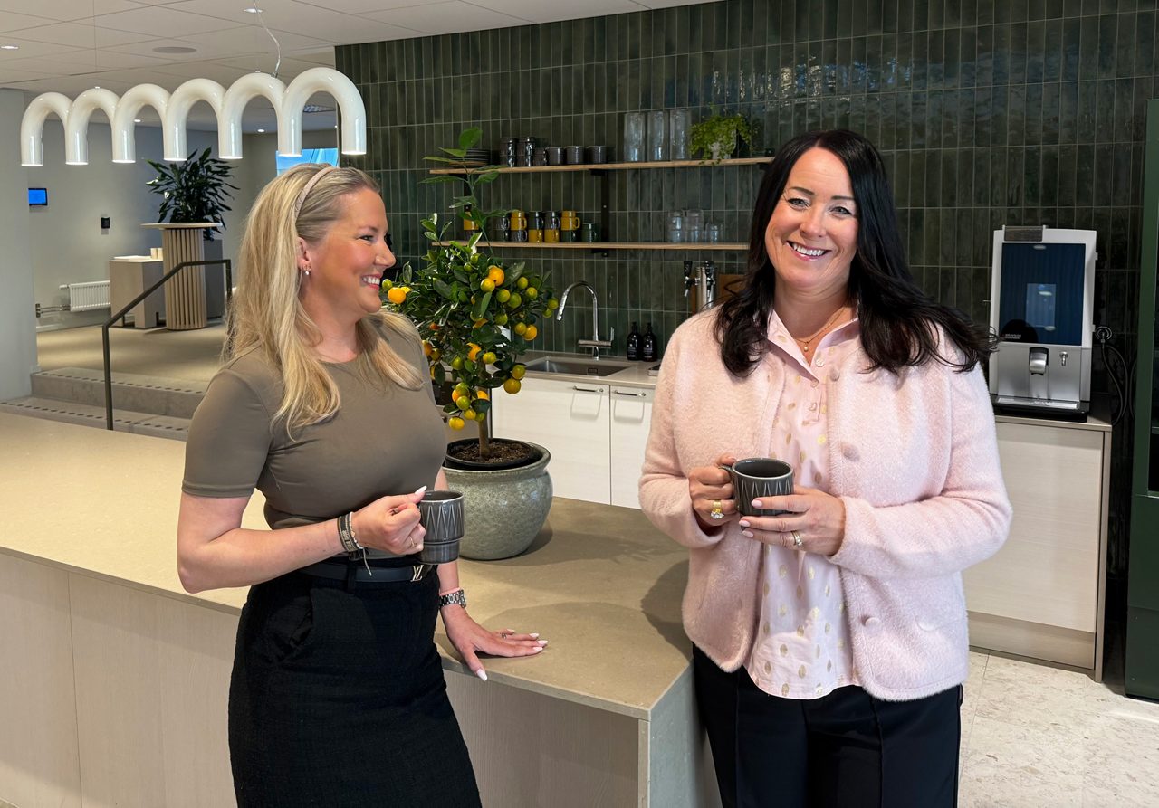 Två kvinnor med varsin kaffekopp står framför en cafedisk