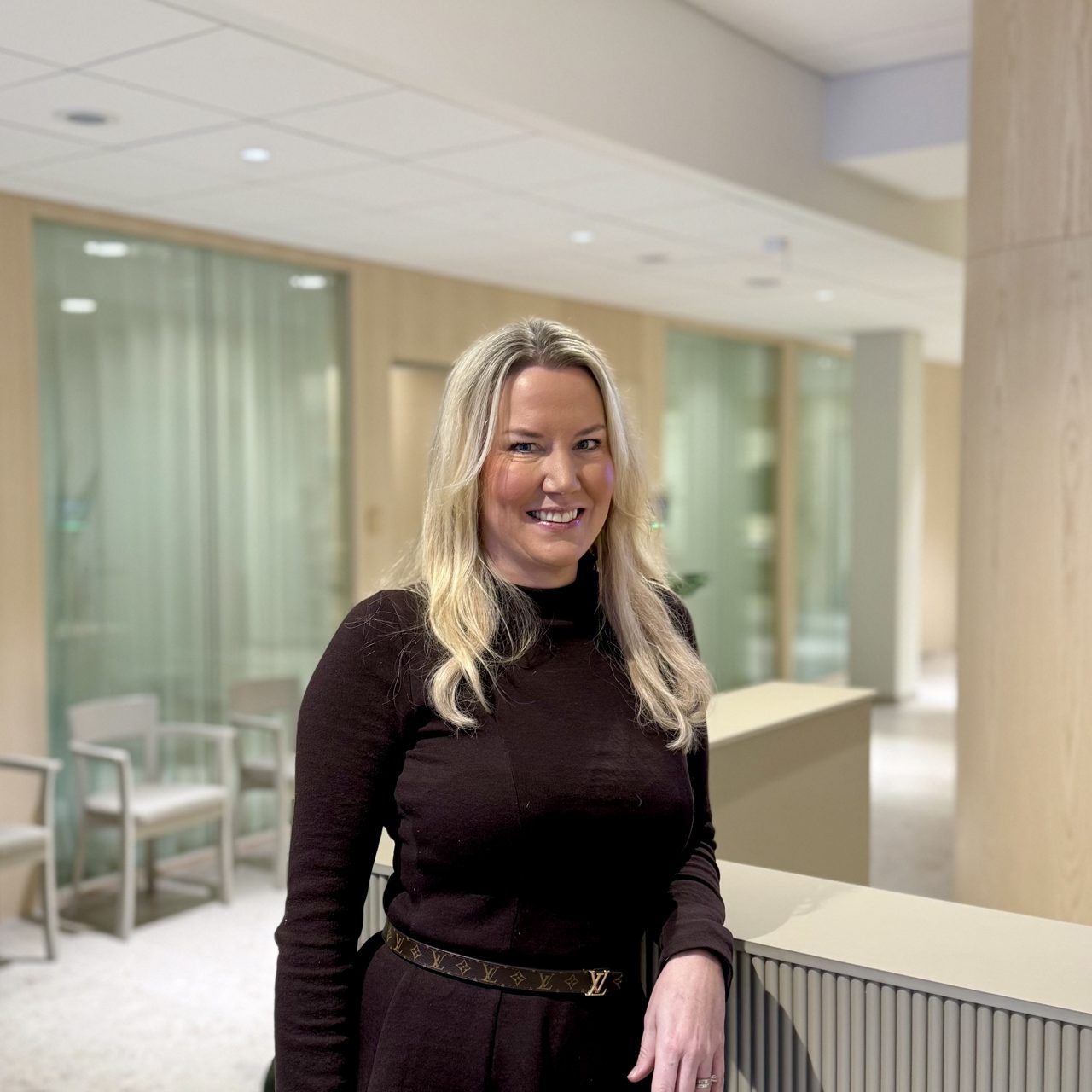 Kvinna står och hänger vid en disk, ler och tittar in i kameran