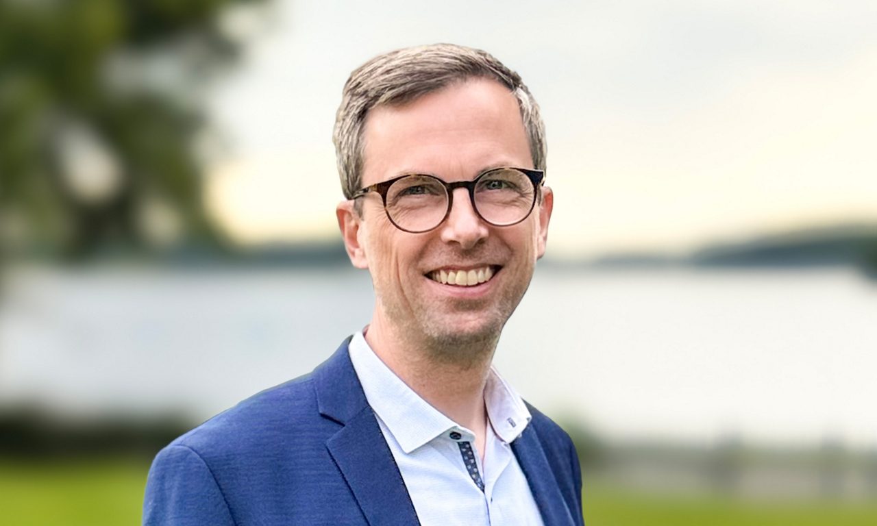 Människor som står och tittar på en brasa utomhus vid en sjö