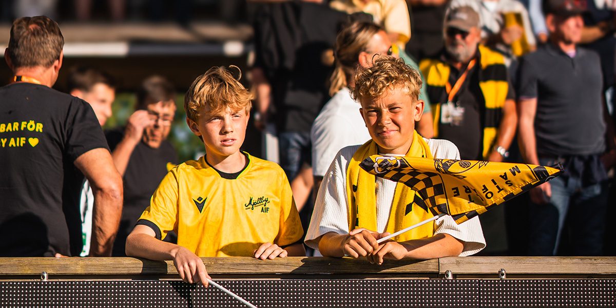 Två unga supportrar viftar med MAIF-flaggor vid sidan av planen