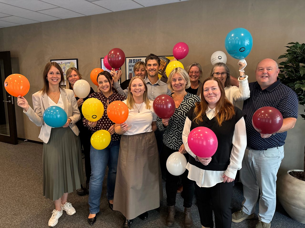 Flera ur personalen ler glatt mot kameran och viftar med ballonger