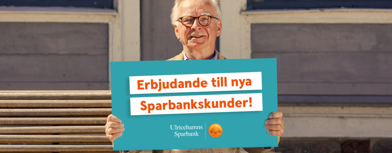 En man sitter på en parkbänk och håller upp ett turkos plakat - text på plakatet: Erbjudande till nya kunder. På plakatet finns även Ulricehamns sparbanks logotype
