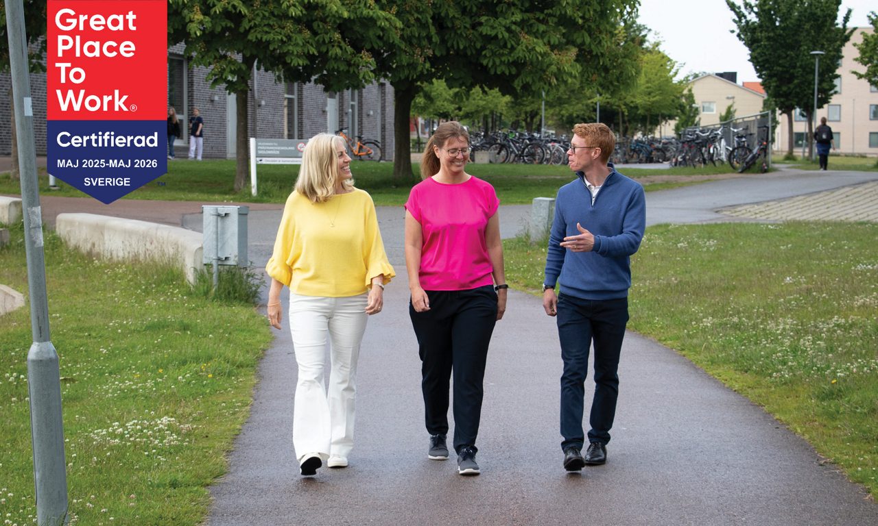 Tre personer promenerar vid dammen