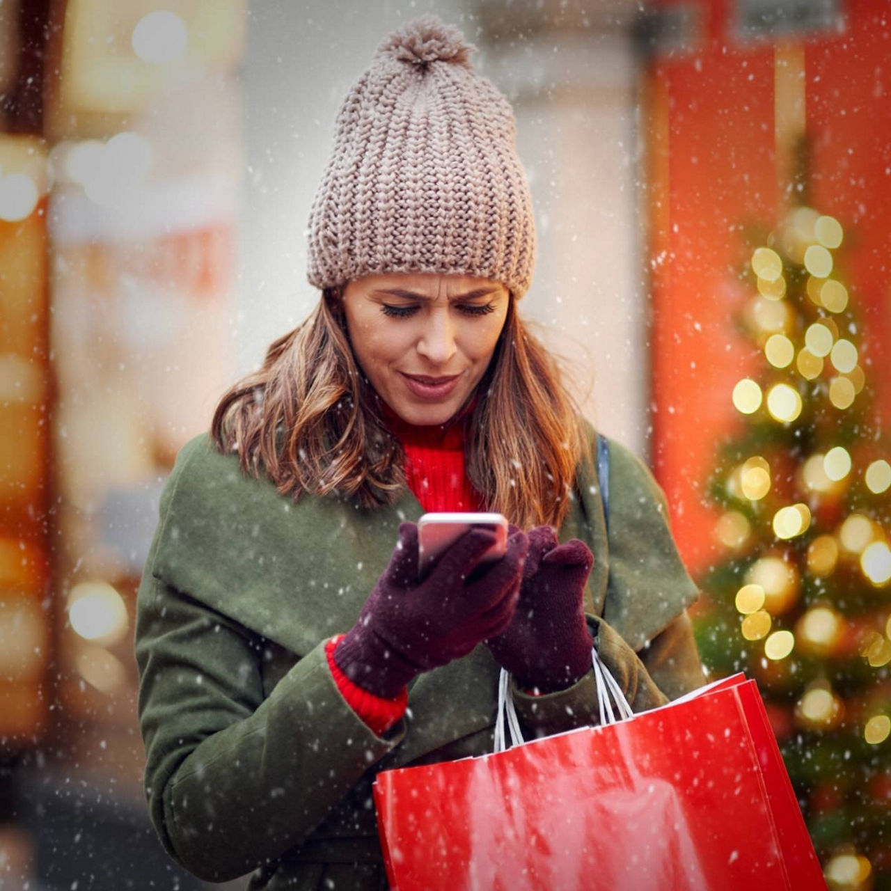 Kvinna tittar på sin mobil och det snöar