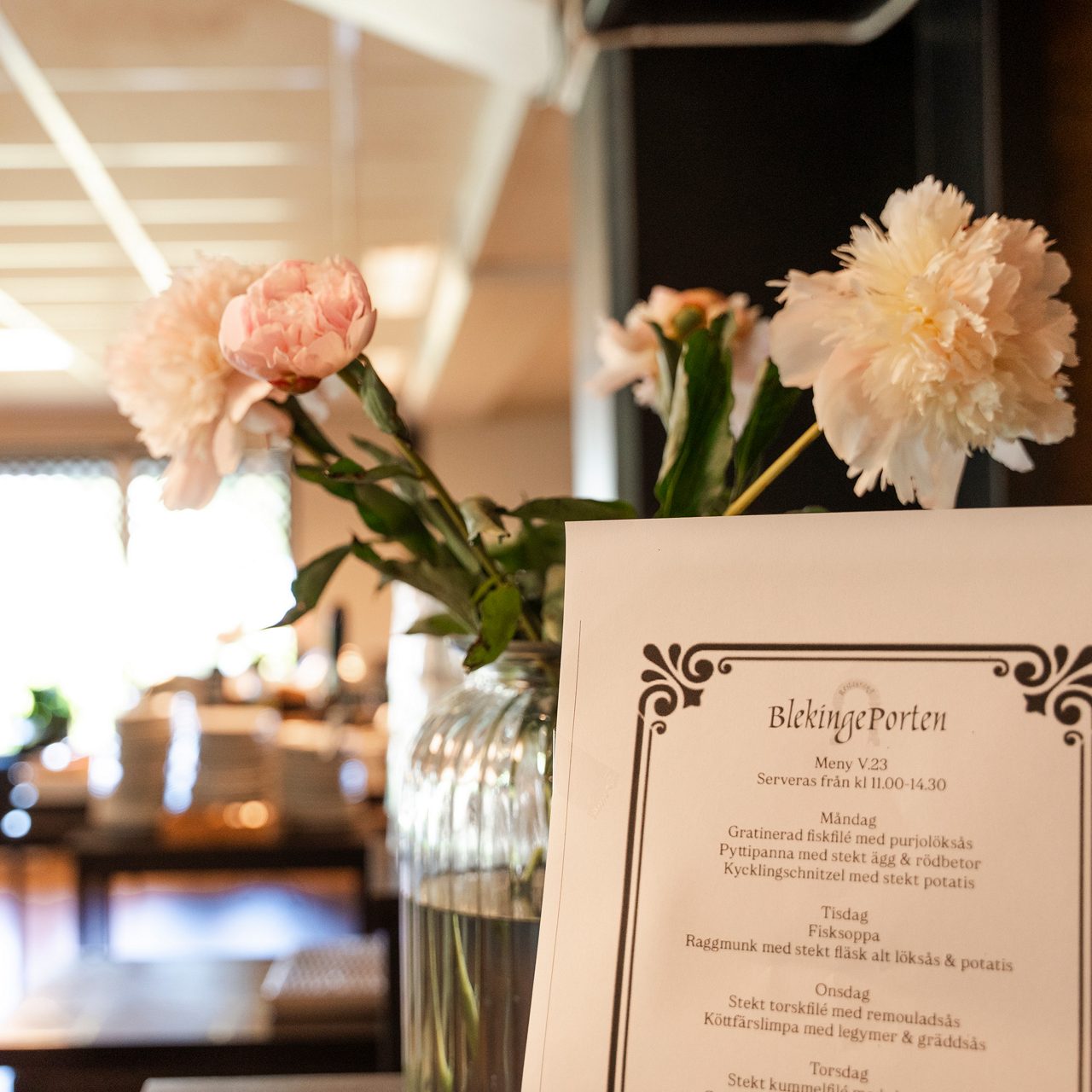 Närbild på blommor i en vas och restaurangens meny