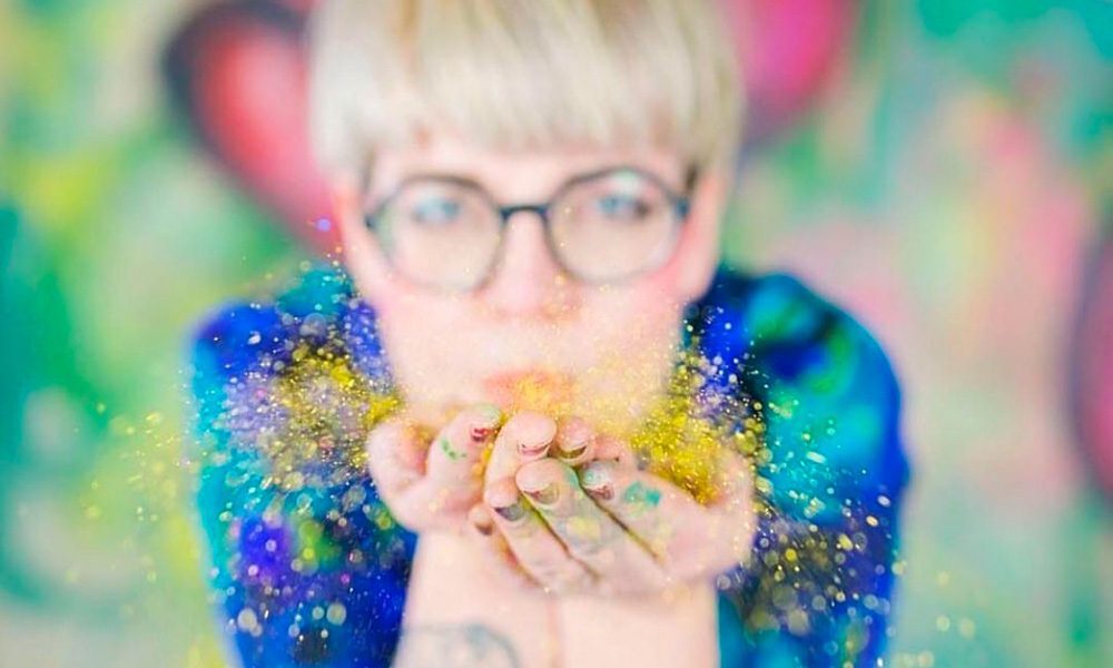 Caroline blåser glitter från händerna mot kameran