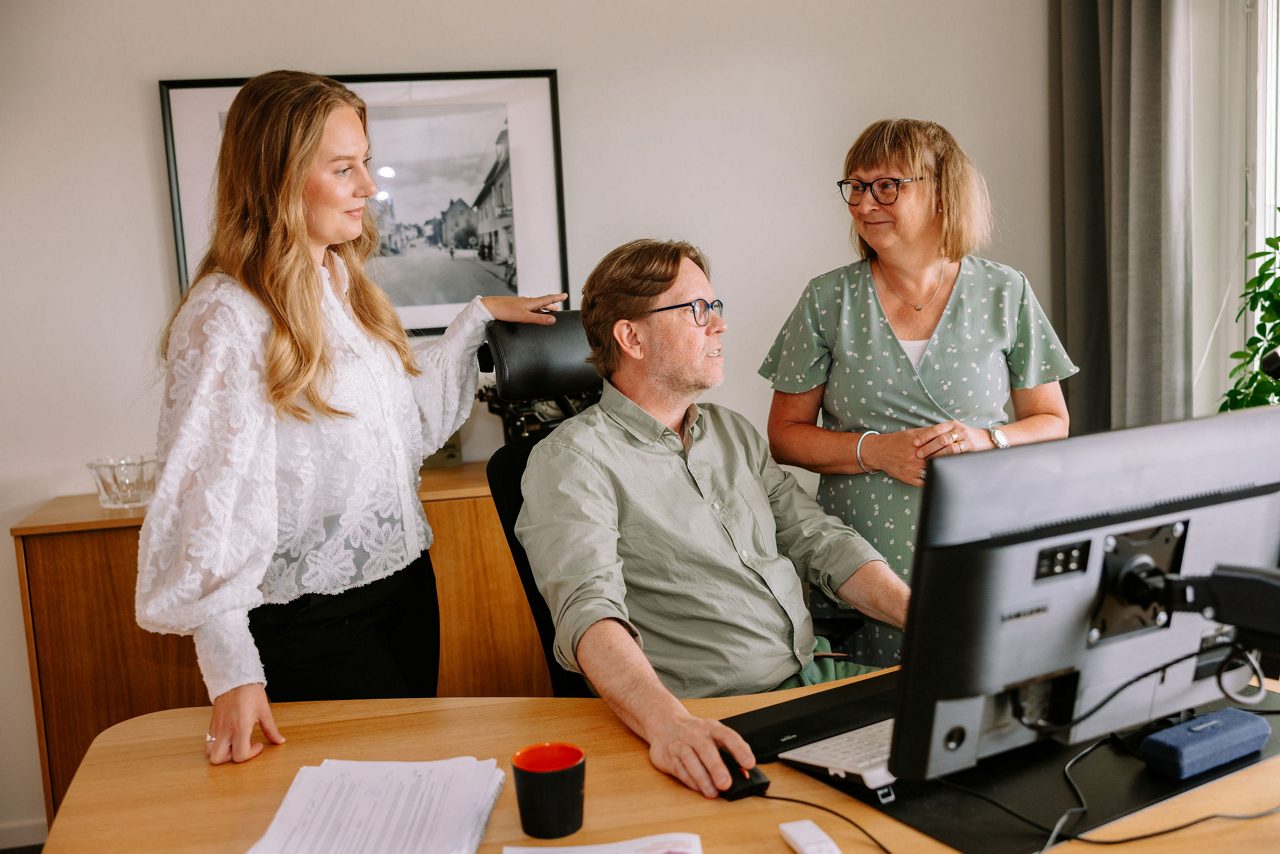 Kollegorna Fanny, Joakim och Fia på ett kontor där de kollar på en skärm och diskuterar.