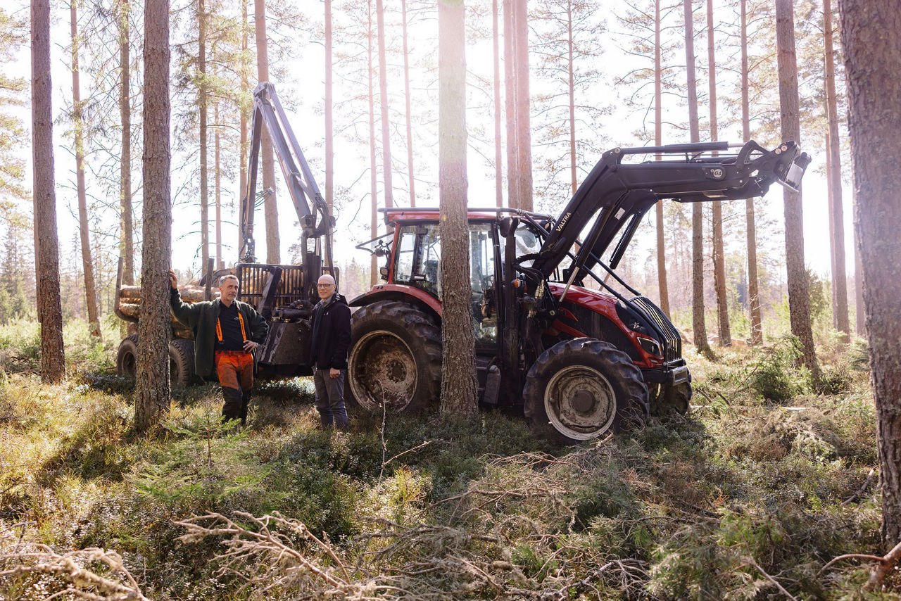 Traktor mitt i skogen, där en skogsarbetare och vår rådgivare John står och diskuterar. 