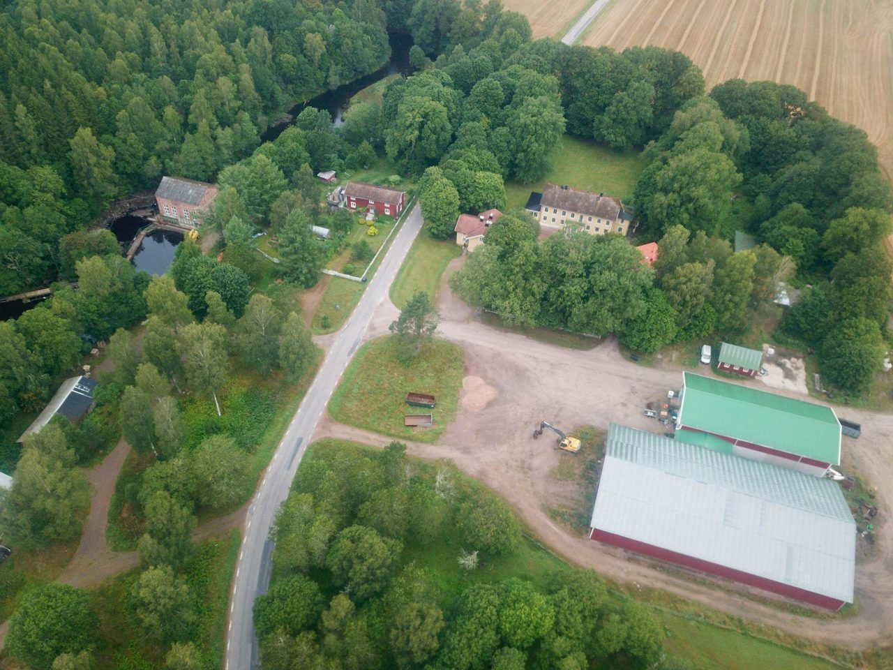 Flygfoto över Mölneby gård där man ser hus, odlingar och skog.