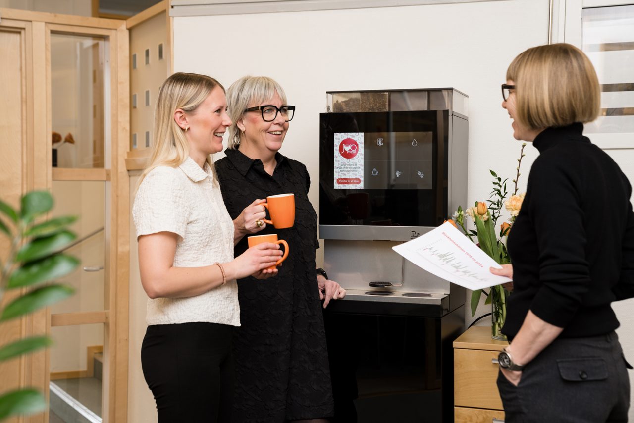 Kollegor på Sparbanken har trevligt samtal vid kaffeautomaten