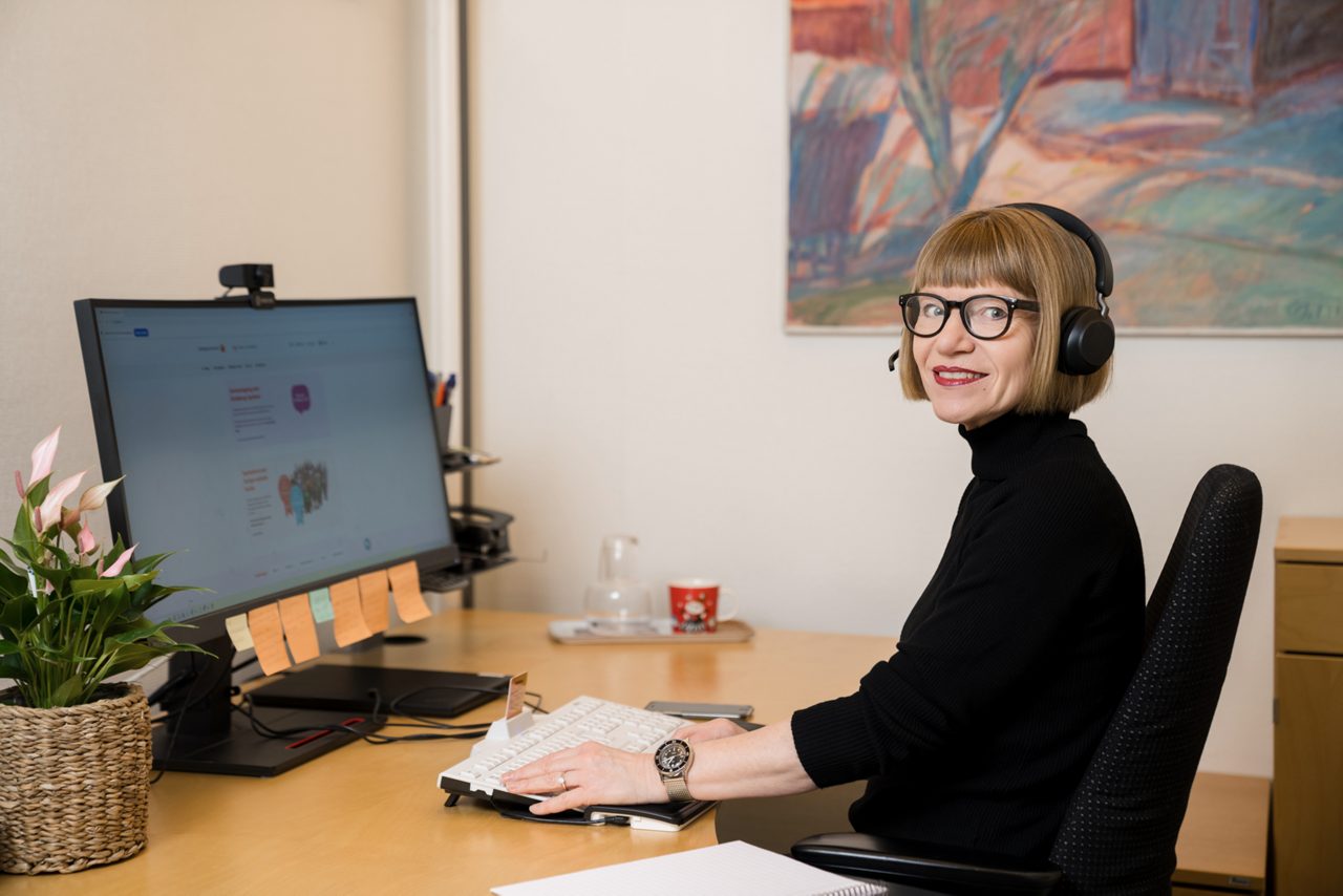Privatrådgivare Susanne arbetar framför sin dator med ett headset