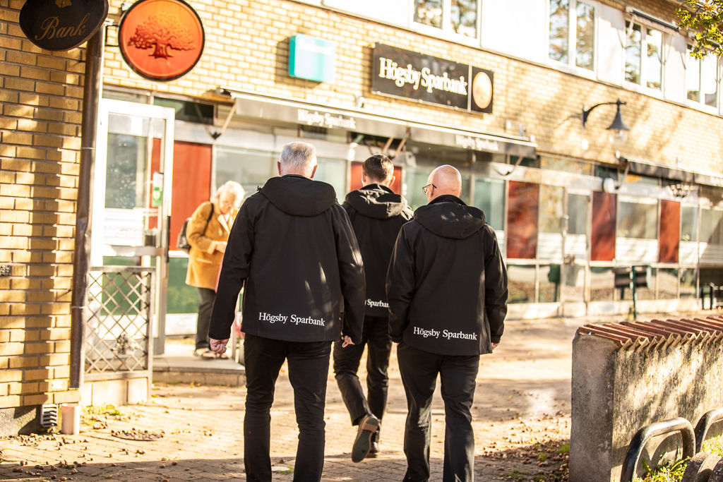 Tre män som går mot bankens lokal 