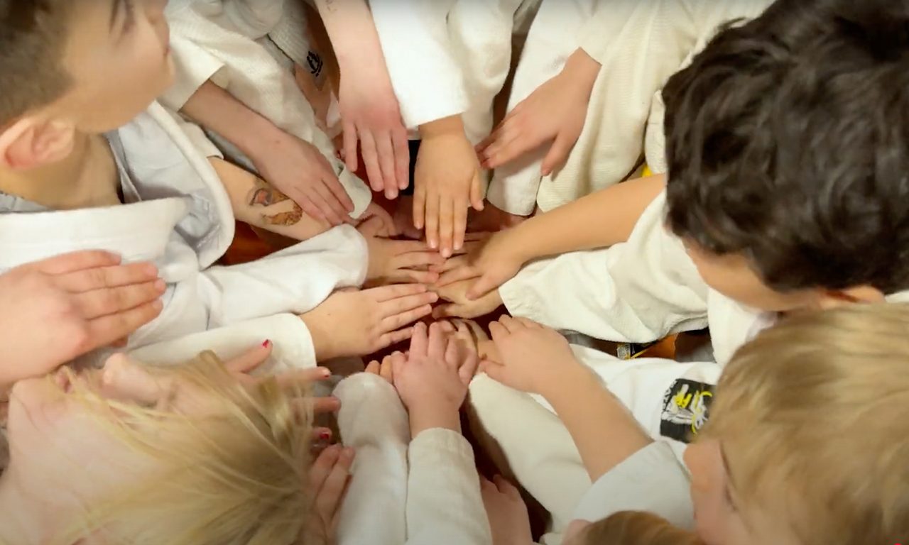 Barn i judokläder håller varandras händer