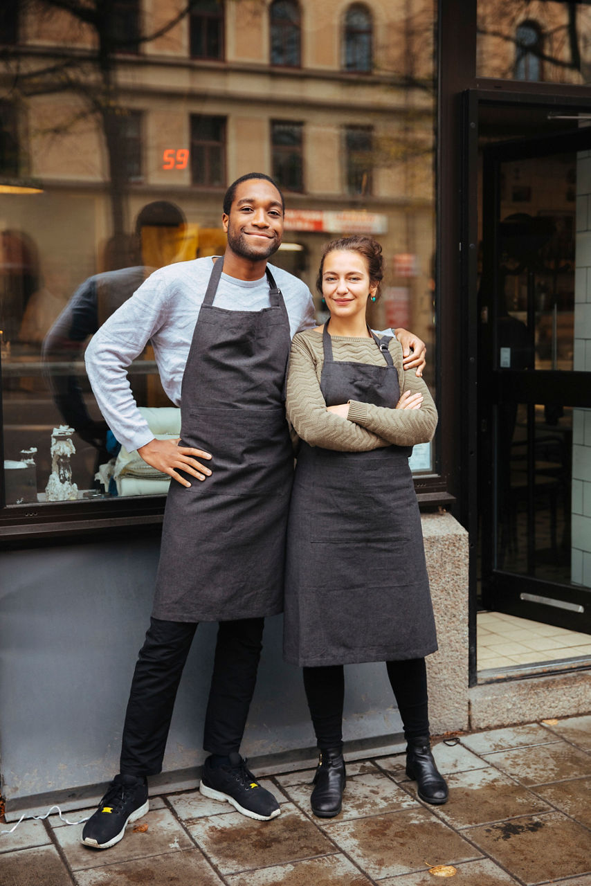 Man och kvinna står utanför ett café, håller om varandra och ler mot kameran