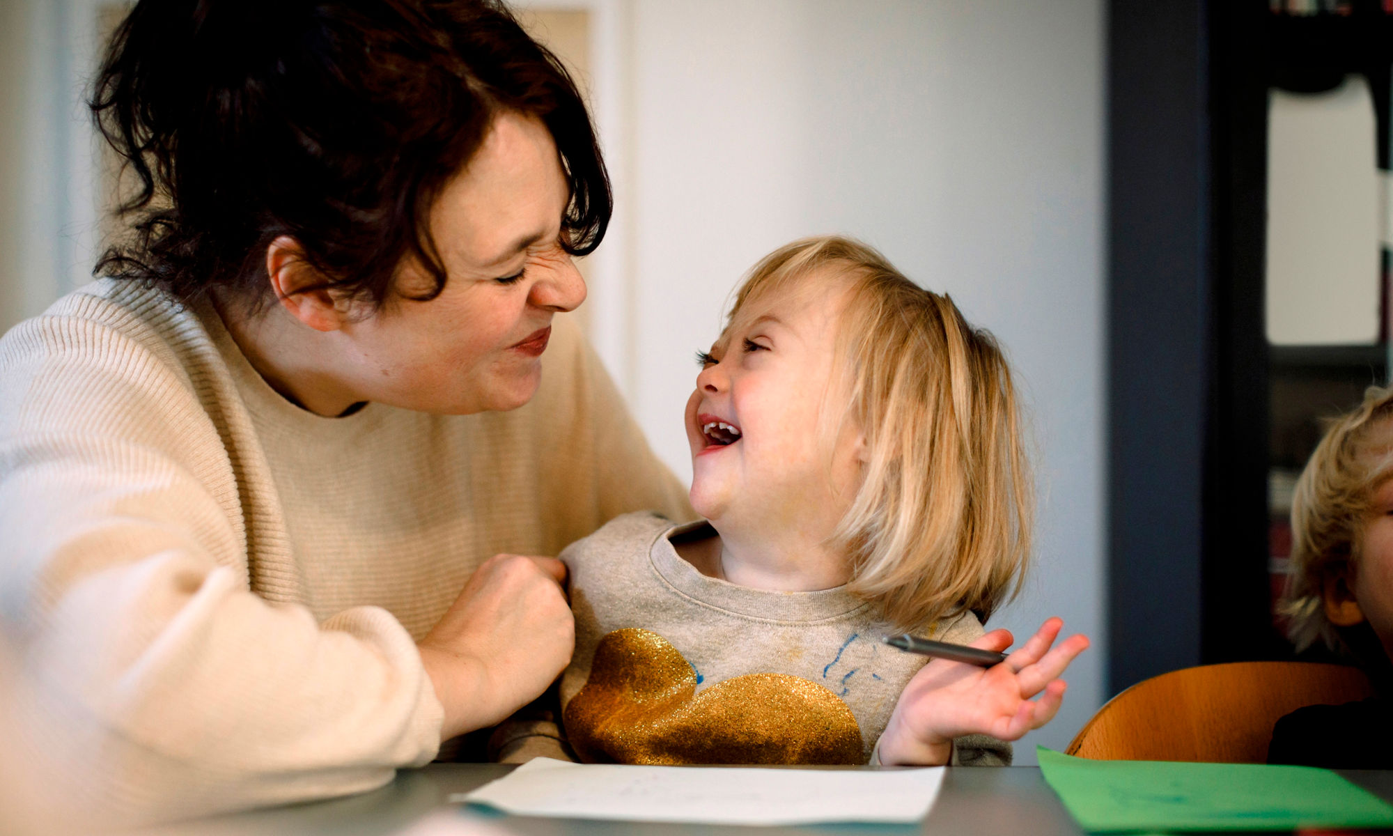 Kvinna och barn sitter och ritar, tittar på varandra och skrattar