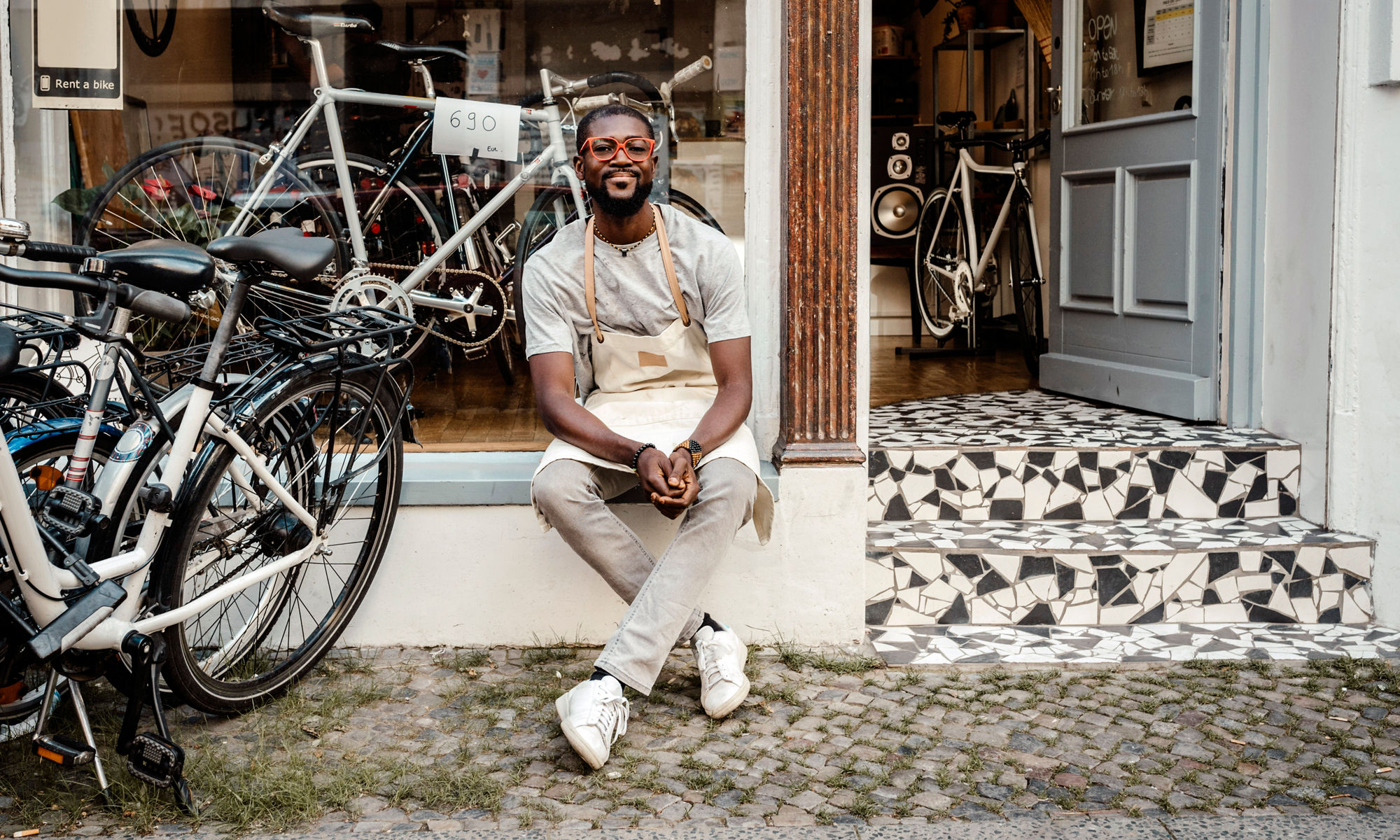 Manlig butiksägare sitter utanför sin cykelaffär