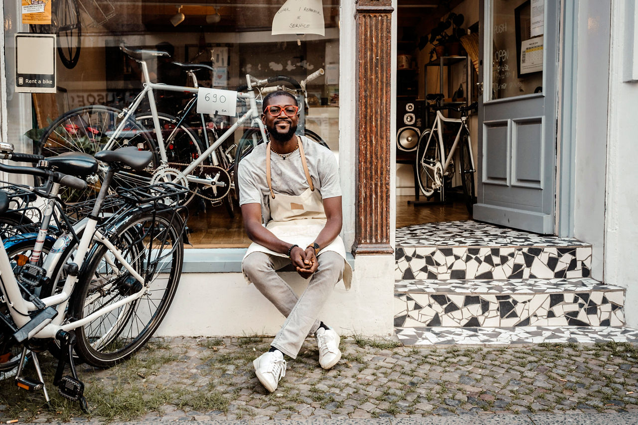 Manlig butiksägare sitter utanför sin cykelaffär