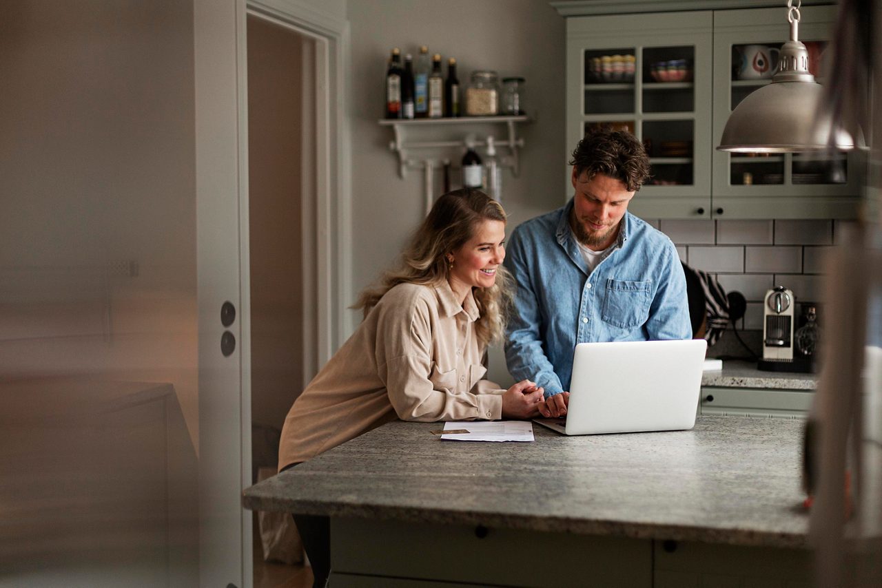 En yngre man talar med en äldre man vid en laptop