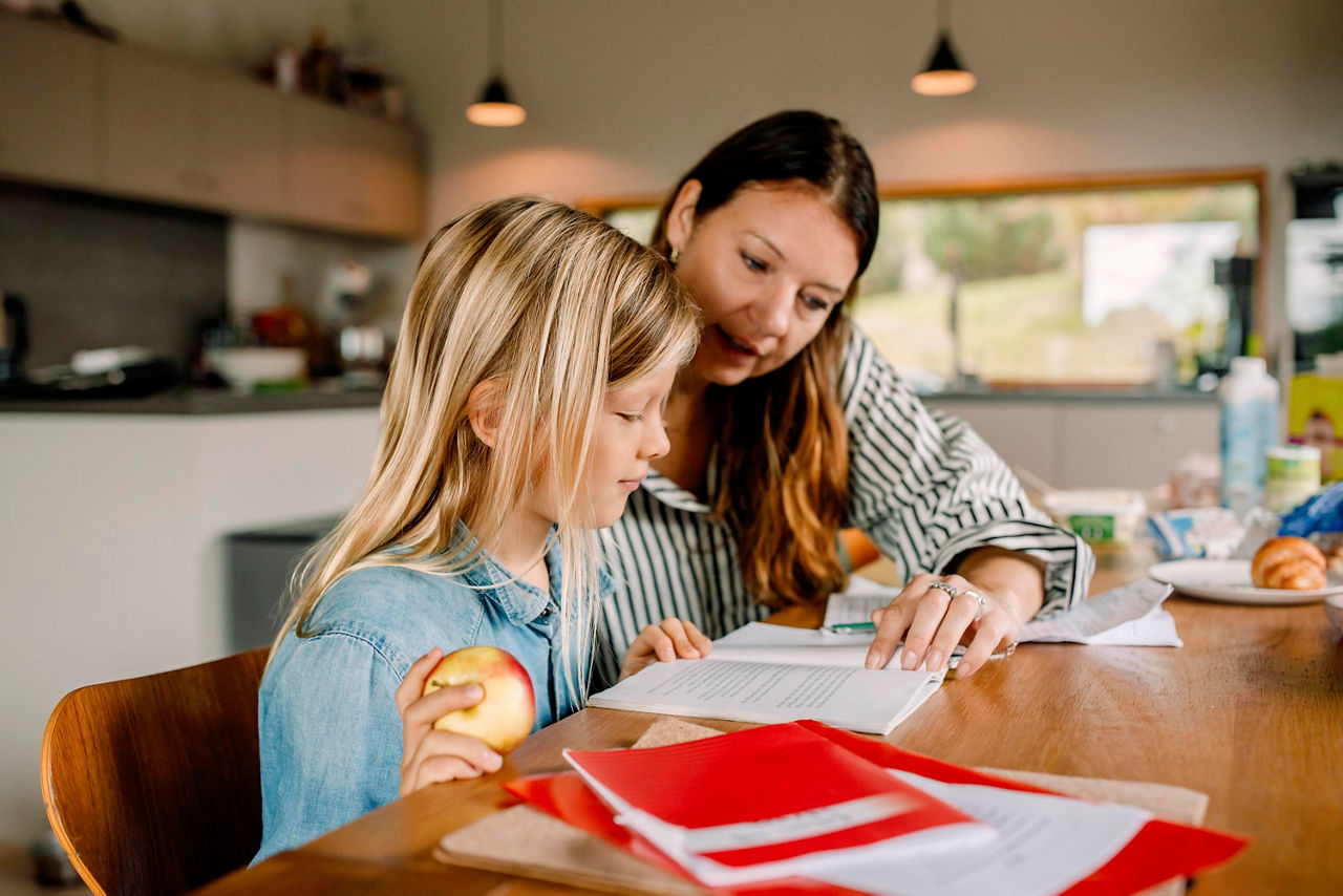 En kvinna och ett barn sitter vid ett bord och läser