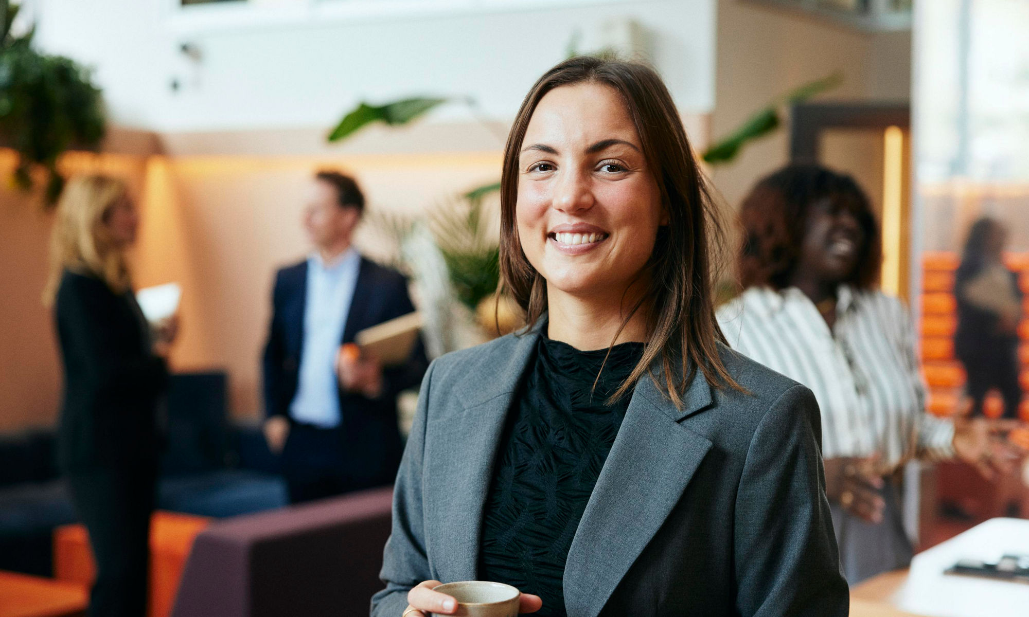 En kvinna håller en kaffekopp i lobbyn på ett kontor