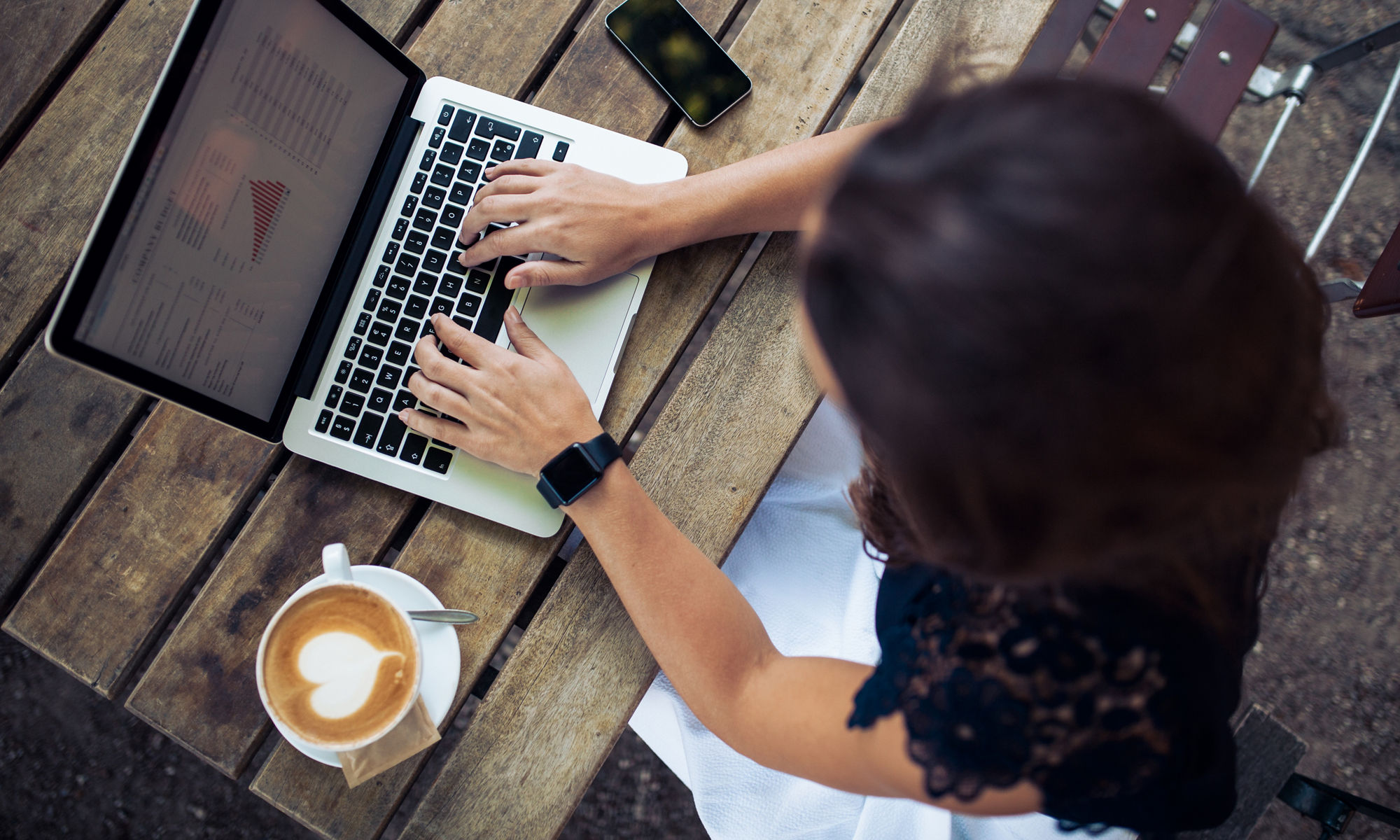 Kvinna sitter med en laptop på ett café