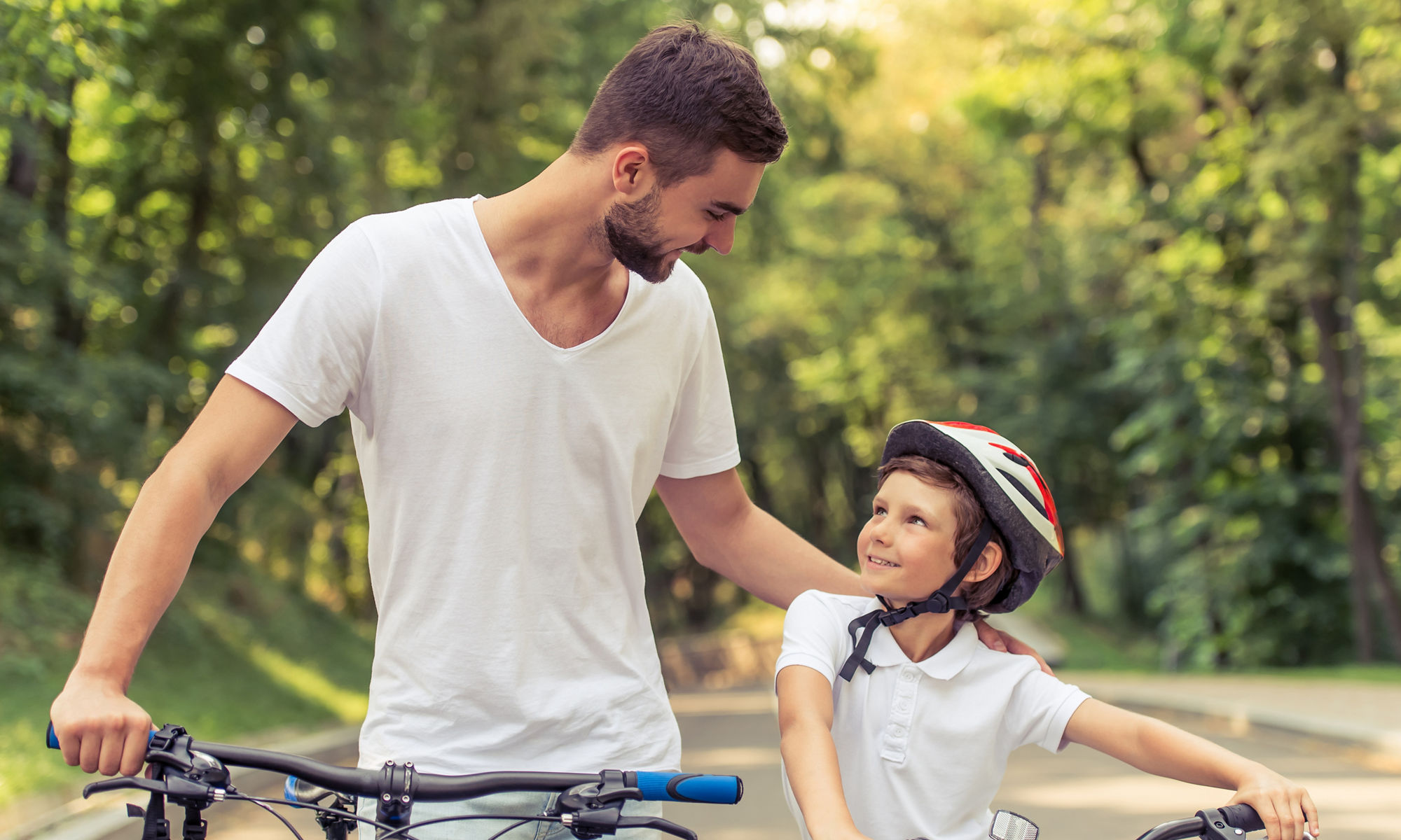 En man och ett barn leder sina cyklar på en väg